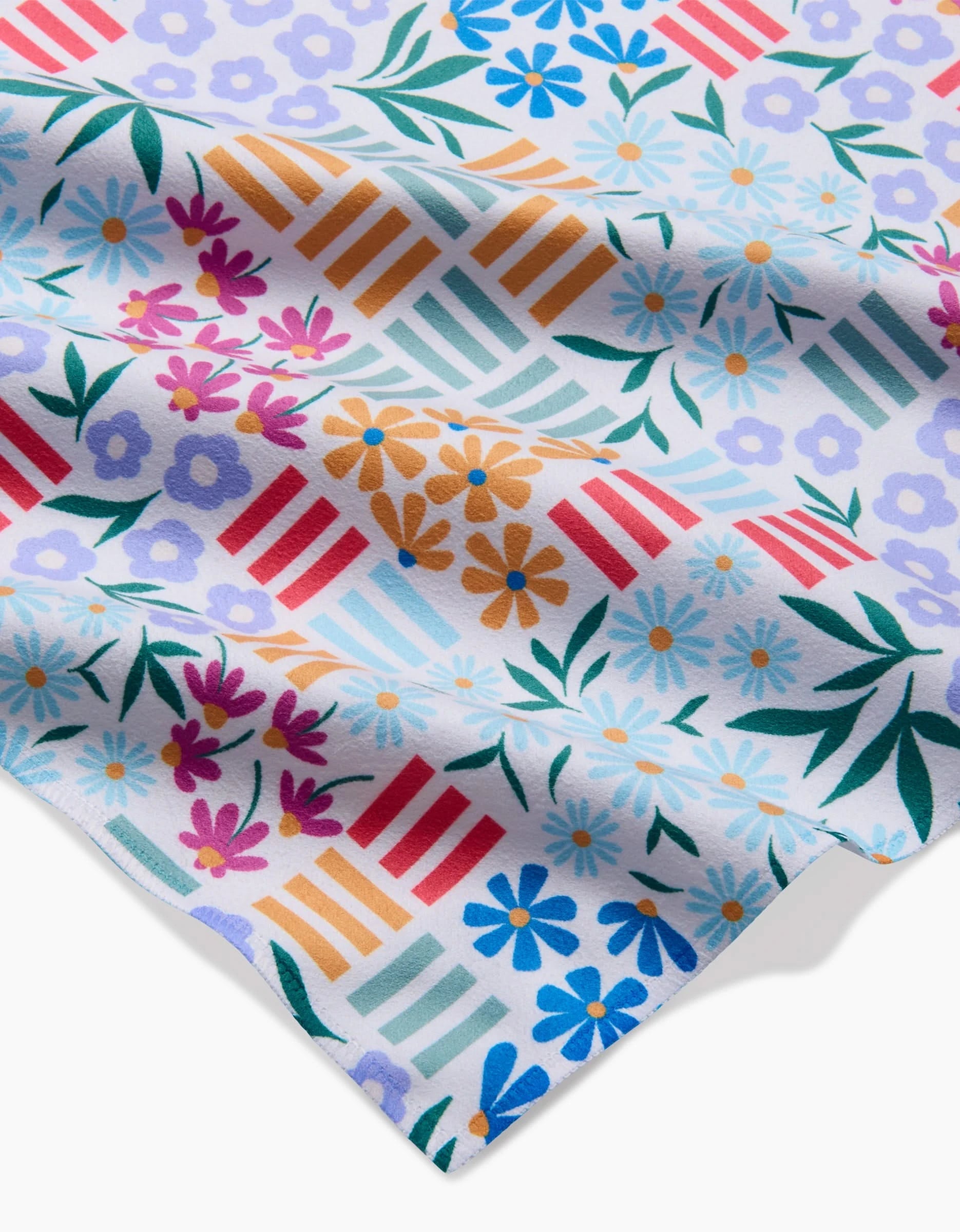 Floral Garden by Charlie Rowan Designs features a slightly wrinkled Geosuede fabric with colorful floral and geometric patterns in blue, red, orange, purple, and green on white—perfect for eco-friendly dinner napkins.
