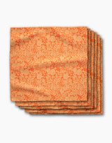 The Florence napkins by Katie OShea are six neatly stacked, eco-friendly orange napkins with a gold floral and vine pattern—stylish dinner décor for any occasion, beautifully displayed against a white background.