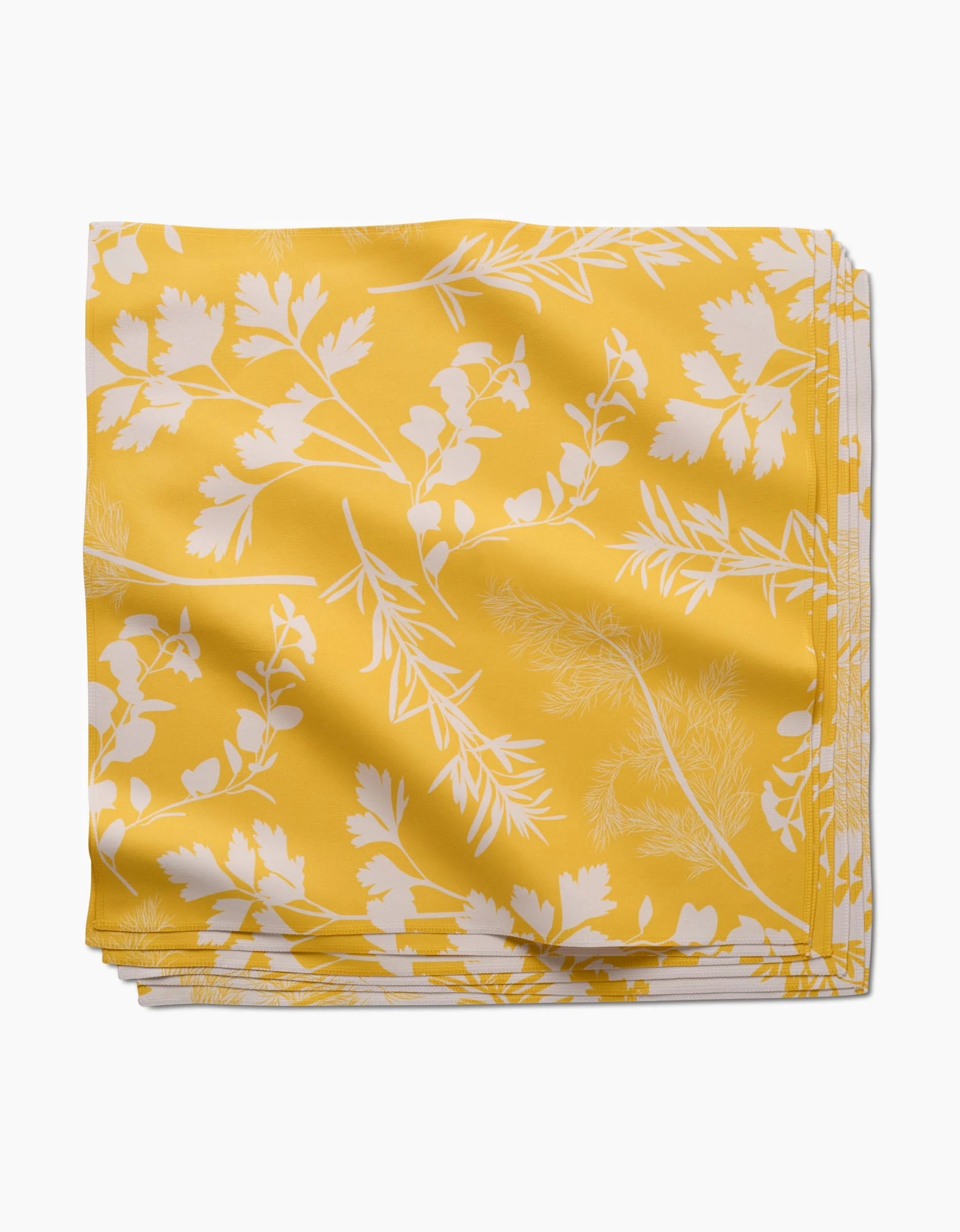 The GEOMETRY Garden of Gold Dinner Napkin, crafted from Geosuede™ fabric, features a white botanical leaf and herb pattern on yellow and is displayed on a white background.