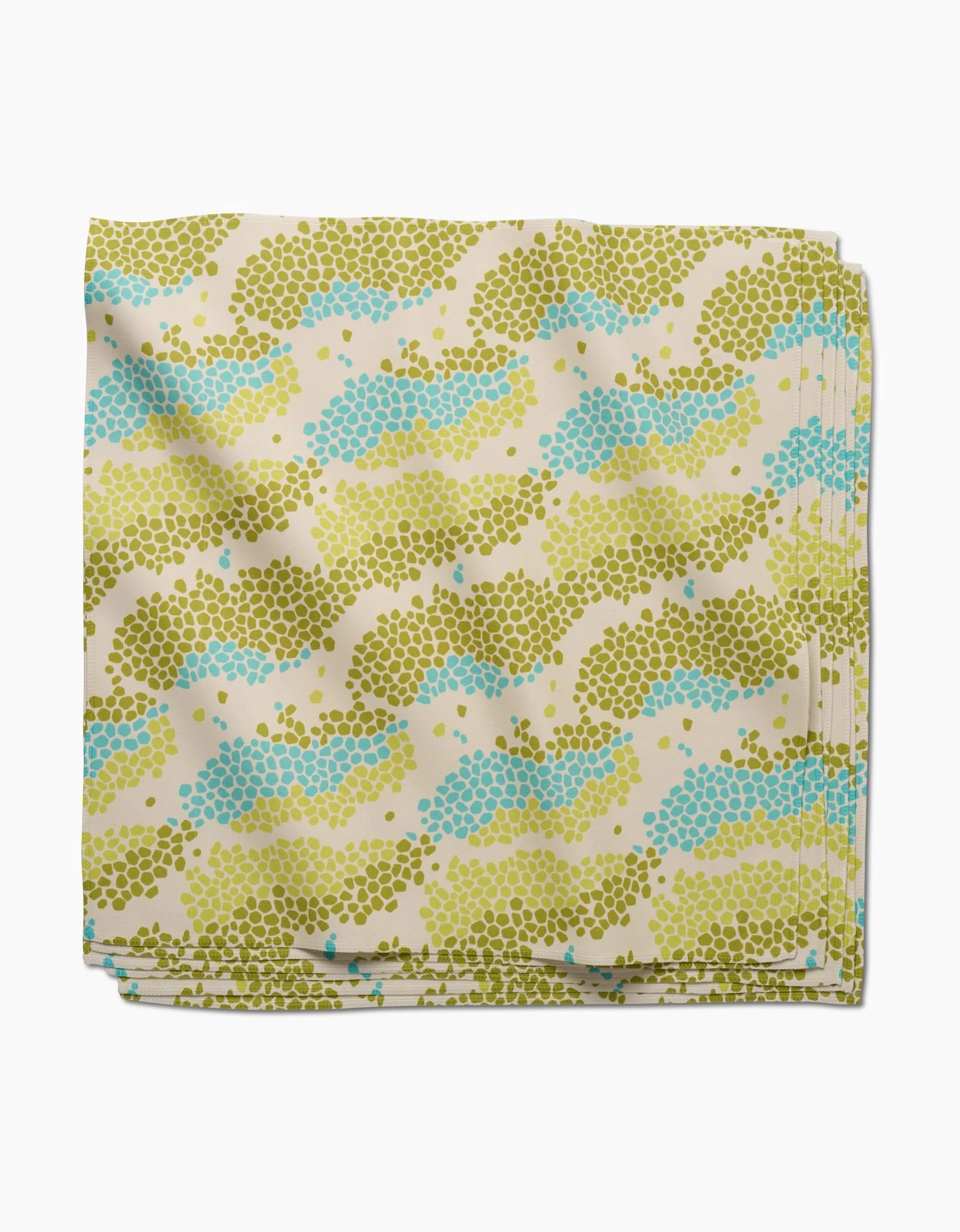 The GEOMETRY Geo Shell dinner napkin set features a folded absorbent cloth with small green, blue, and yellow dots in wavy lines on a cream background—stylish and practical for any table.