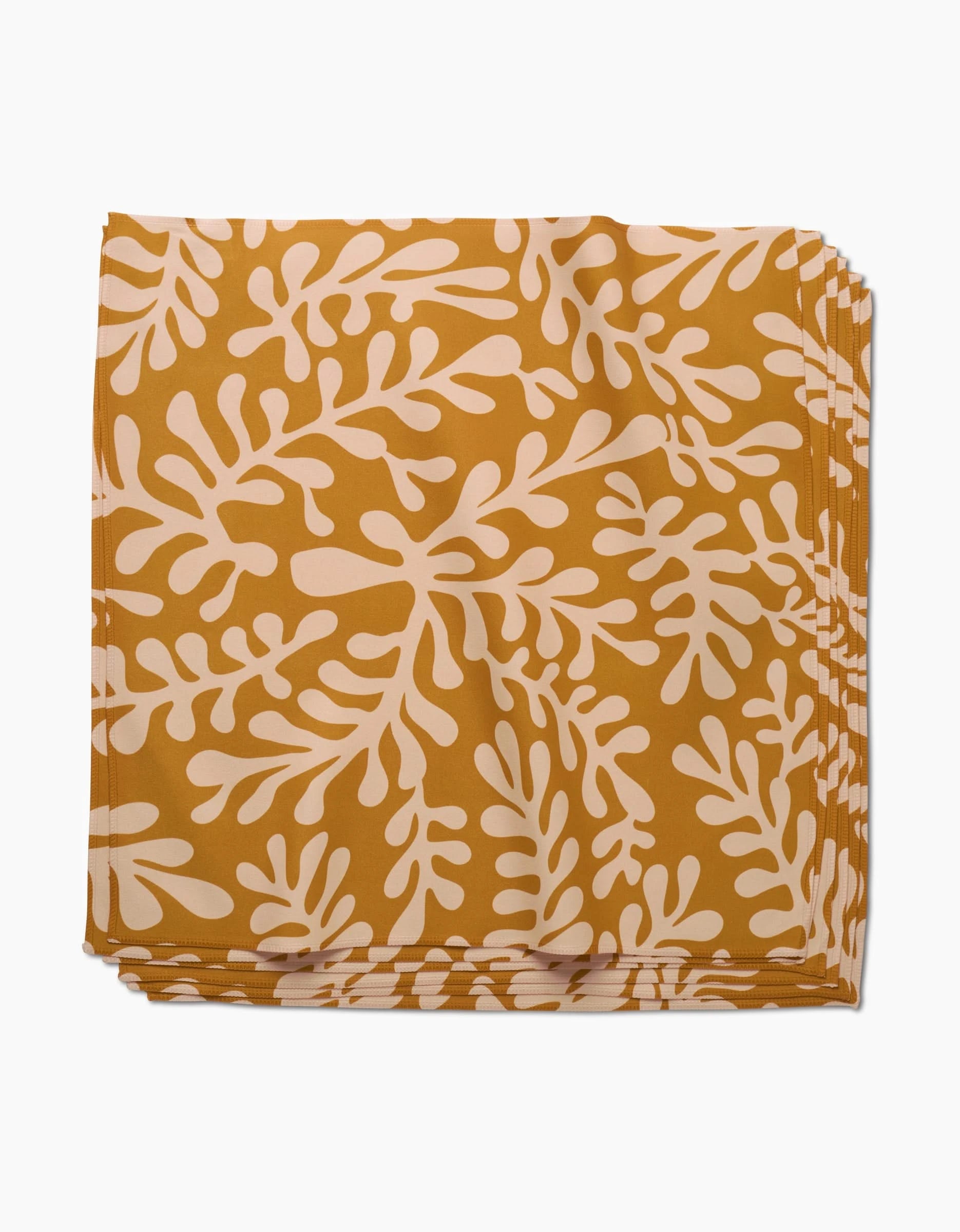The GEOMETRY Golden Fall dinner napkin, crafted from folded mustard yellow Geosuede fabric with a cream abstract leafy or coral design, is shown against a white background.