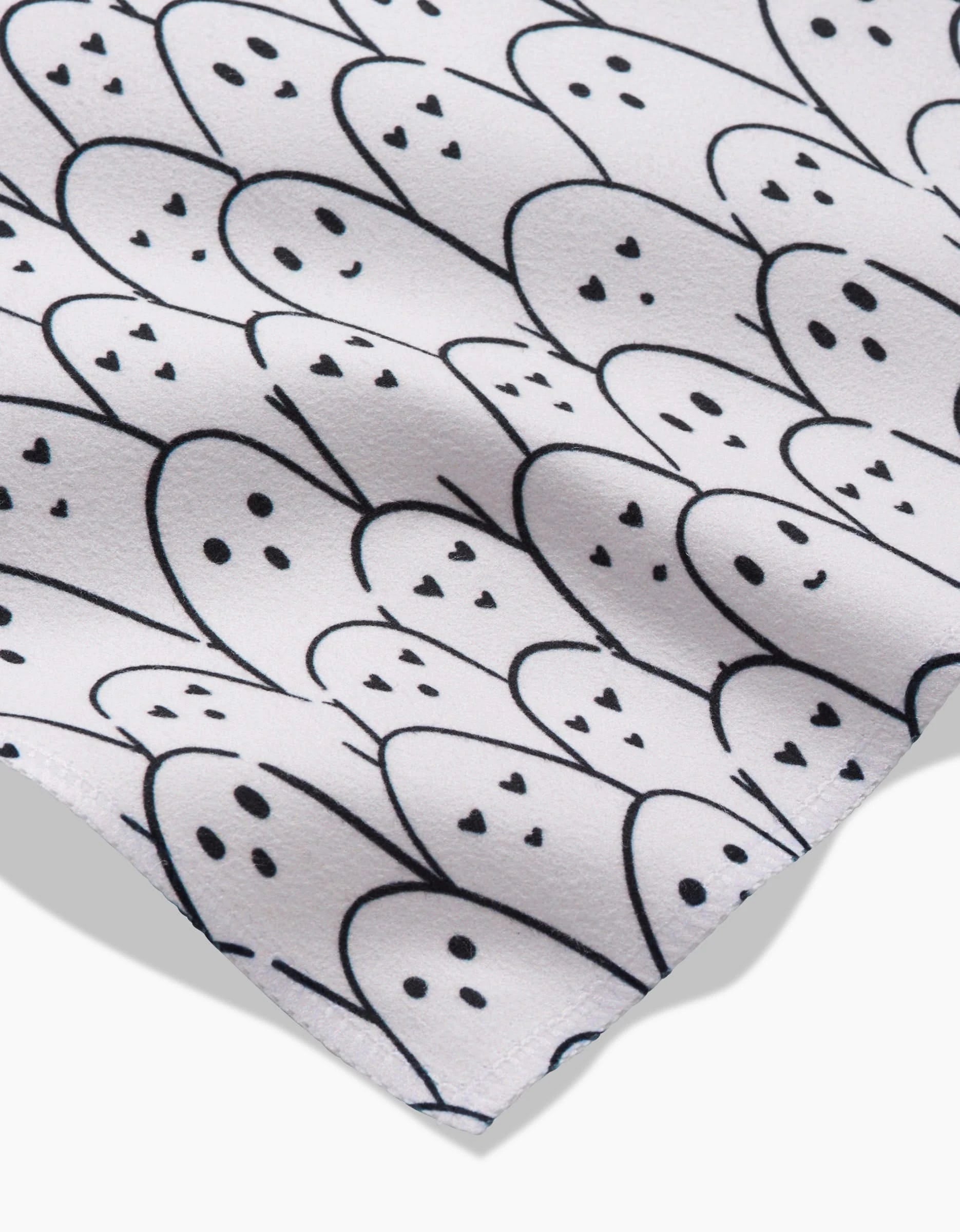 A close-up of Hufton Studios Happy Ghosts napkins, featuring a repeating pattern of simple black-outlined ghosts with small eyes and smiley faces on white, eco-friendly material.