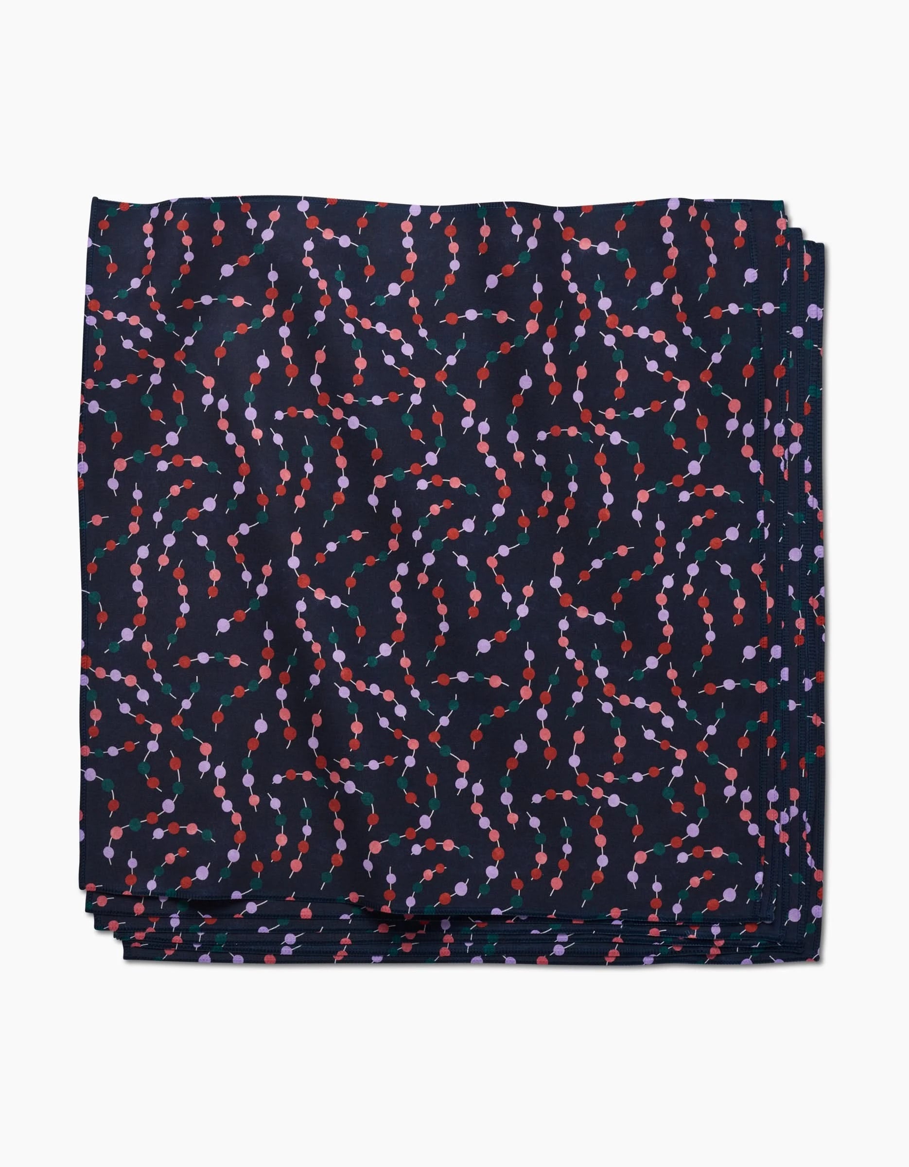 Claire Iglesias Holiday Garland Dinner Napkin Set, crafted from Geosuede fabric, features a folded design with wavy, colorful lines and small red, purple, and pink circles on a crisp white background.