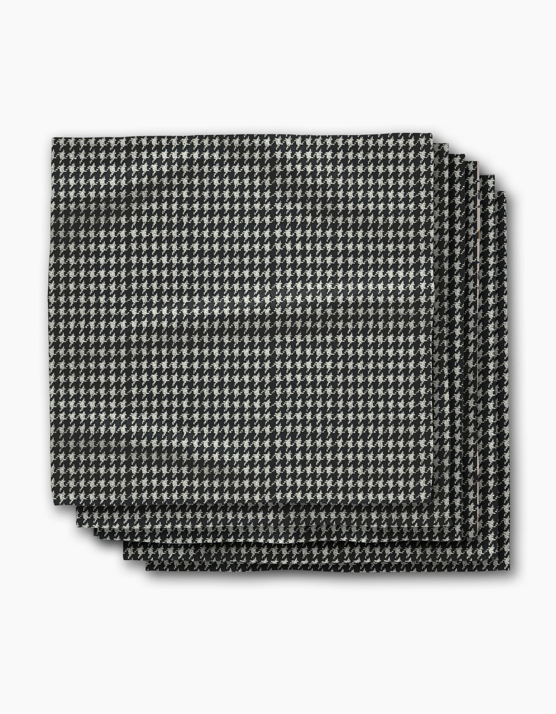 Four neatly stacked rectangular napkins from Geometry, featuring the Houndstooth Black pattern, are displayed against a plain white background.