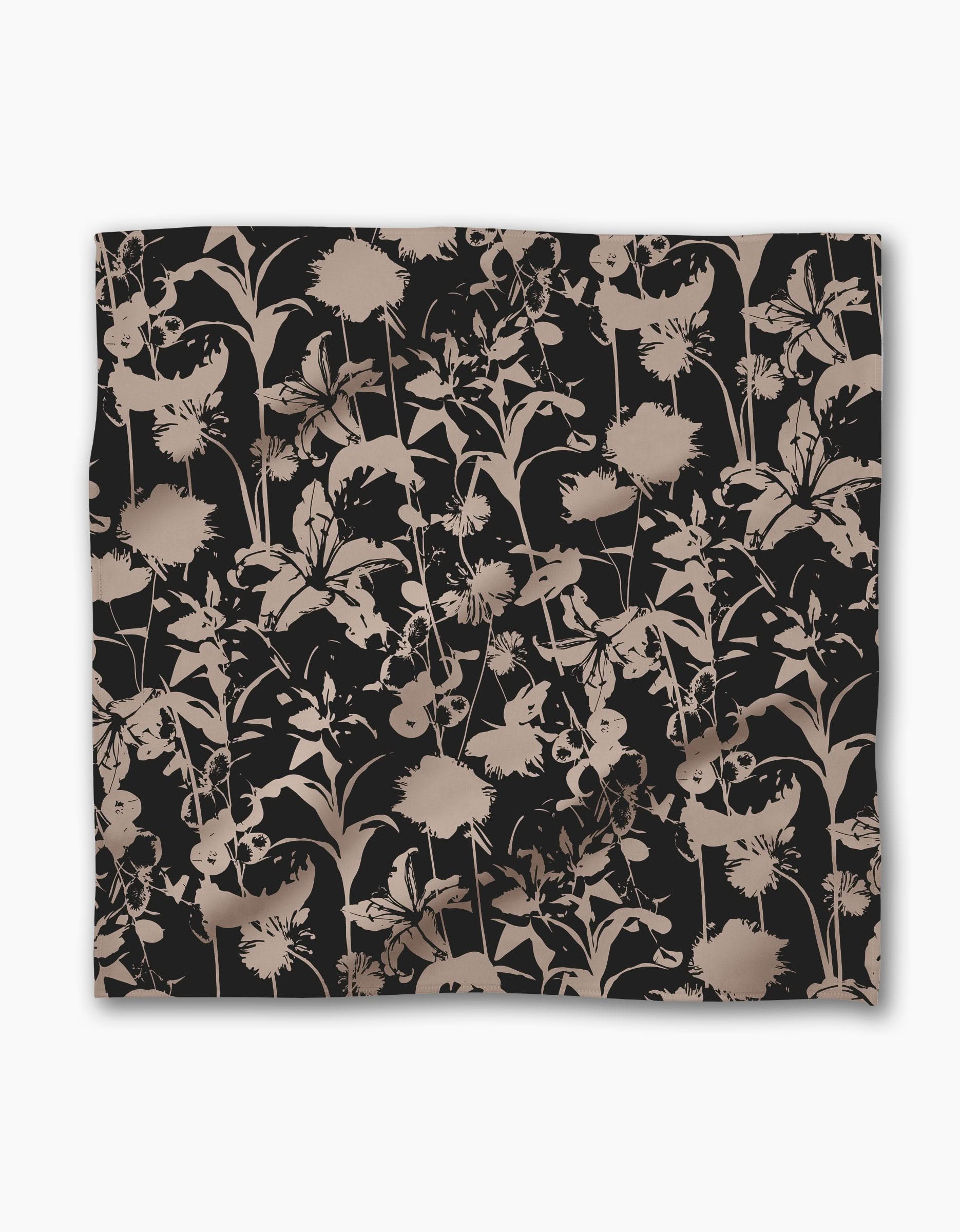 The Geometry Inverted Floral Black blanket showcases a beige and taupe floral silhouette on a black Geosuede fabric, with overlapping flowers and leaves for an elegant look.
