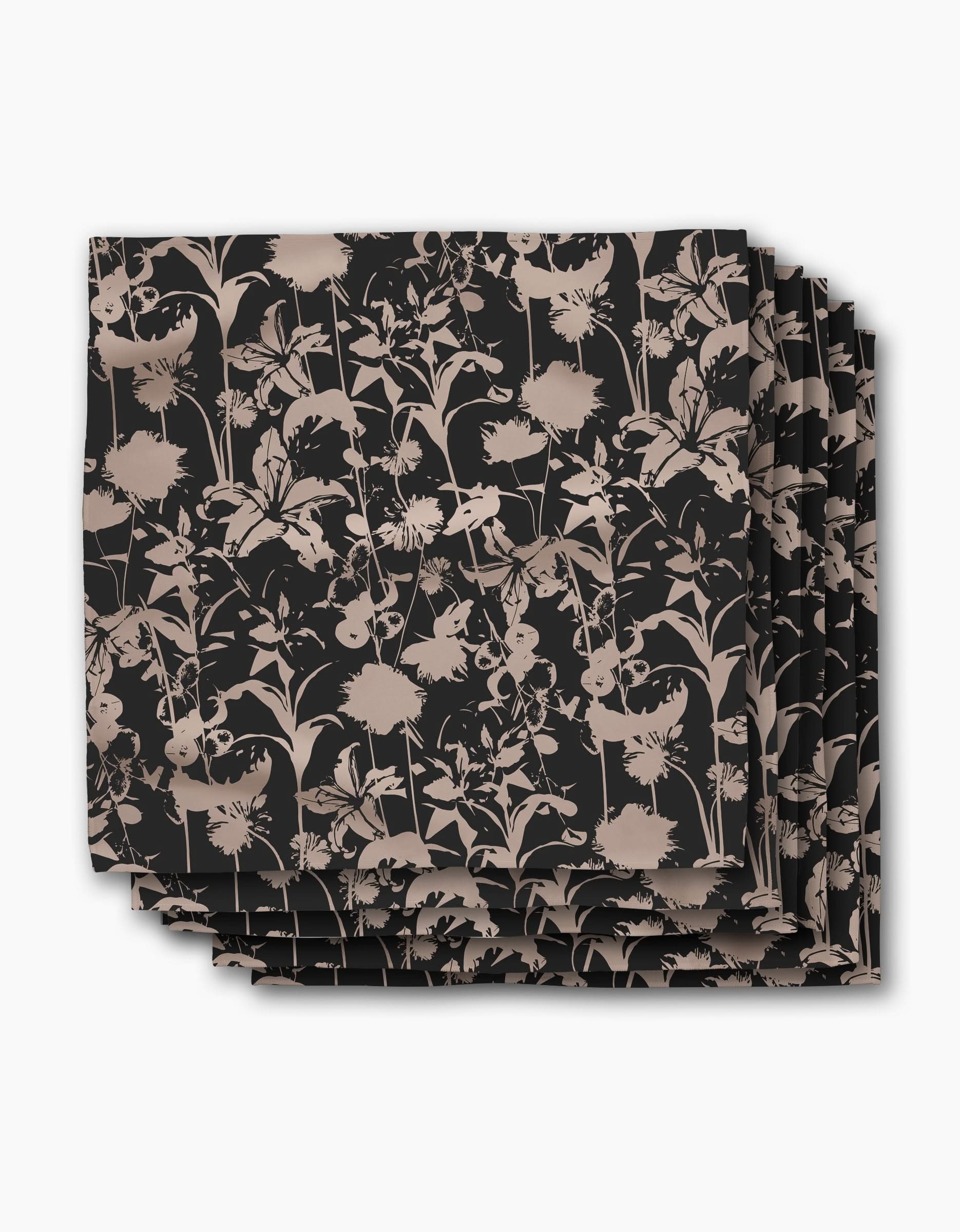 A set of four square recycled dinner napkins by Geometry, named Inverted Floral Black, featuring a beige floral pattern with assorted flowers and leaves on a black background.