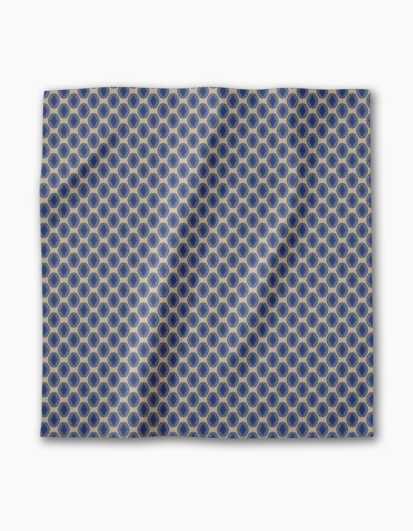 The Lagoon dinner napkin by Geometry is a blue fabric square with interlocking gold hexagons, shown flat with subtle folds and shadows. This absorbent cloth napkin is part of an elegant dining set.