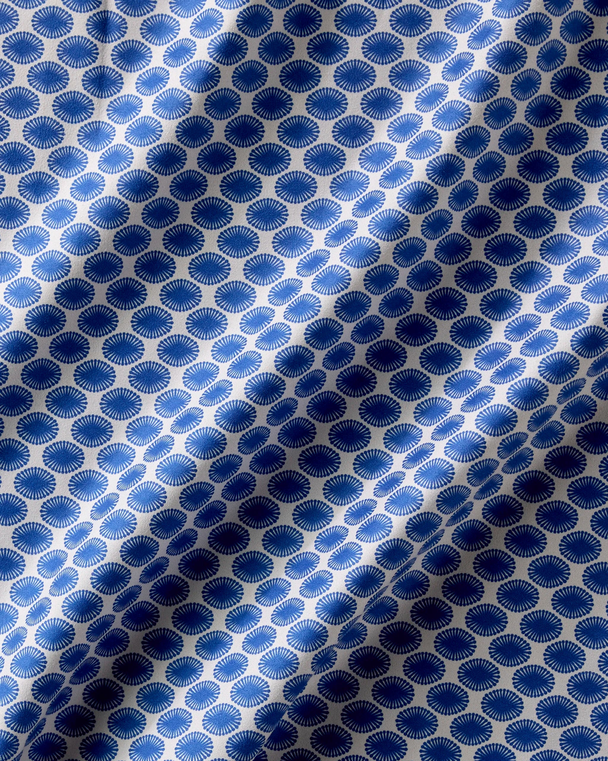 Lagoon by Geometry features blue and white patterned fabric with circular designs and radiating lines. Soft shadows create a wavy effect, making these reusable napkins a stylish touch to any dinner napkin set.