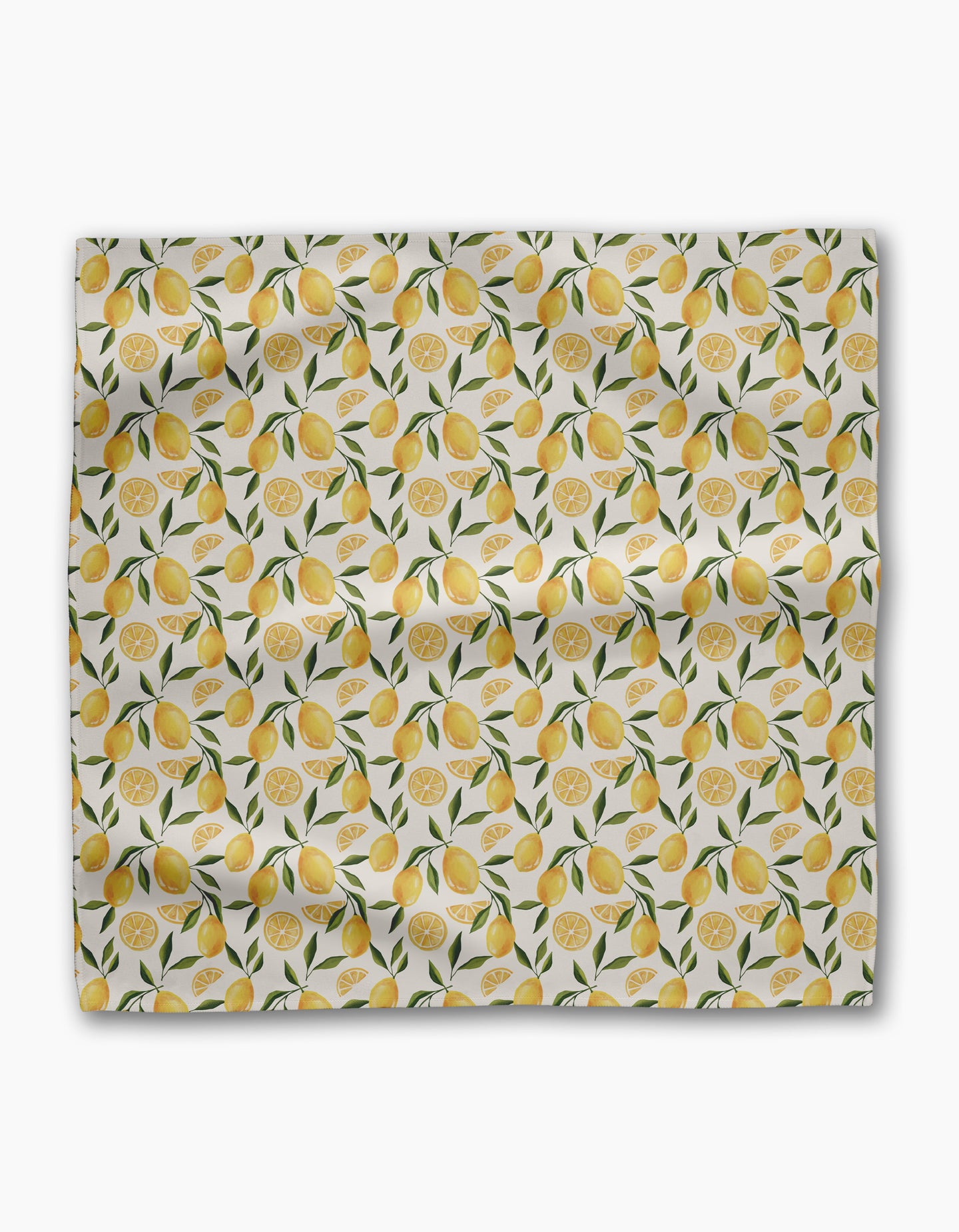 Geometry’s Limoncello Geosuede fabric features whole lemons, lemon slices, and green leaves on a white background—slightly wrinkled and displayed flat, ideal for creating a lively set of dinner napkins.