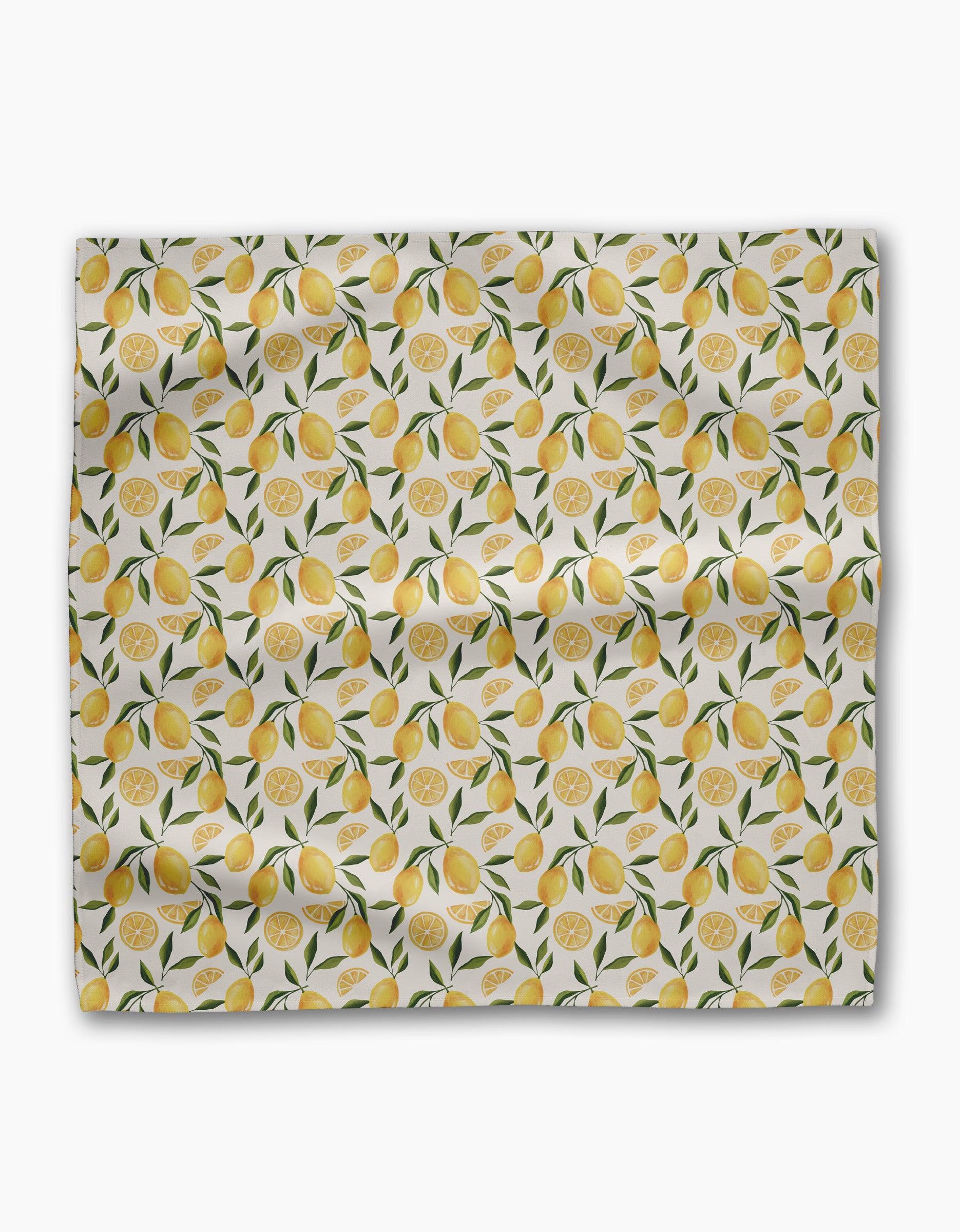 Geometry’s Limoncello Geosuede fabric features whole lemons, lemon slices, and green leaves on a white background—slightly wrinkled and displayed flat, ideal for creating a lively set of dinner napkins.