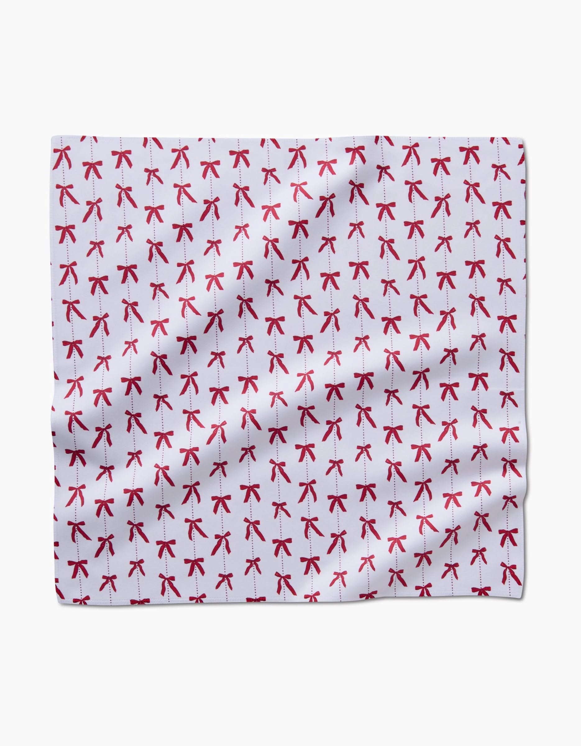 Little Bows And Pearls by Hufton Studio features white Geosuede fabric adorned with a repeating pattern of small red bows, evenly spaced across the surface, and subtle wrinkles and folds.