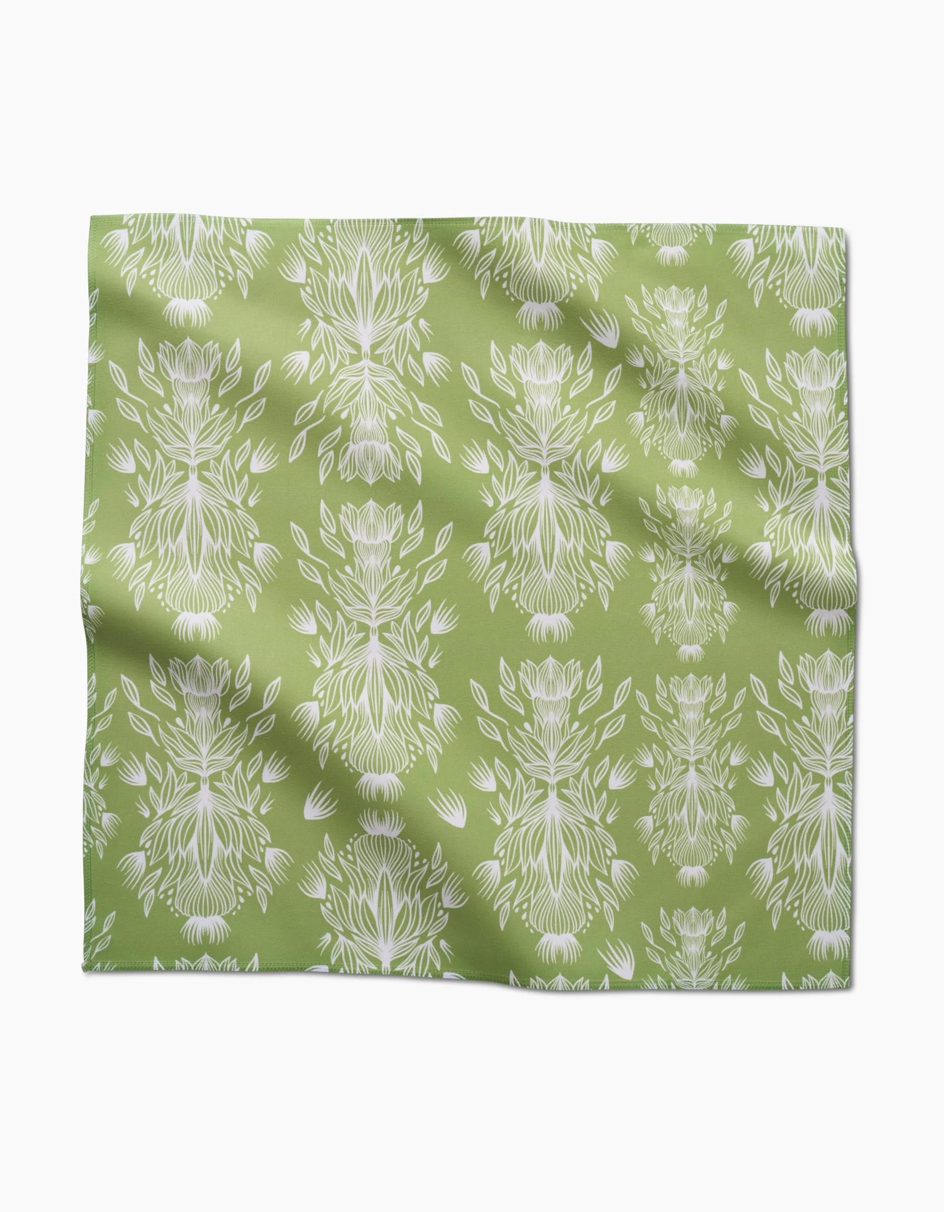 Margarita Vibes by GEOMETRY features green Geosuede fabric with a repeating white floral and leaf print, subtle folds and creases, and is crafted from recycled materials for eco-friendly style.