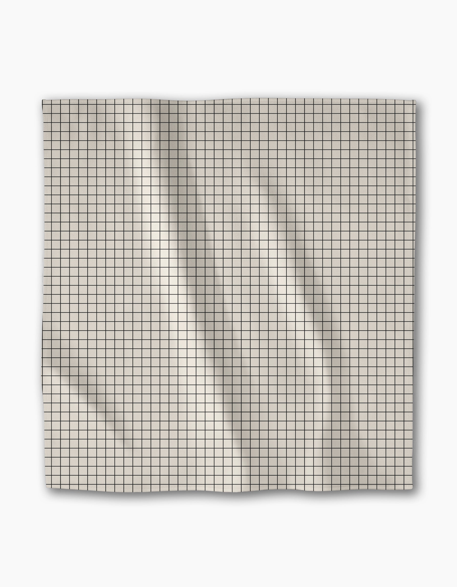 The Geometry Metro Grid dinner napkin features light-colored Geosuede fabric in a square shape with a small black grid pattern, displayed flat on a white background showing creases and folds.