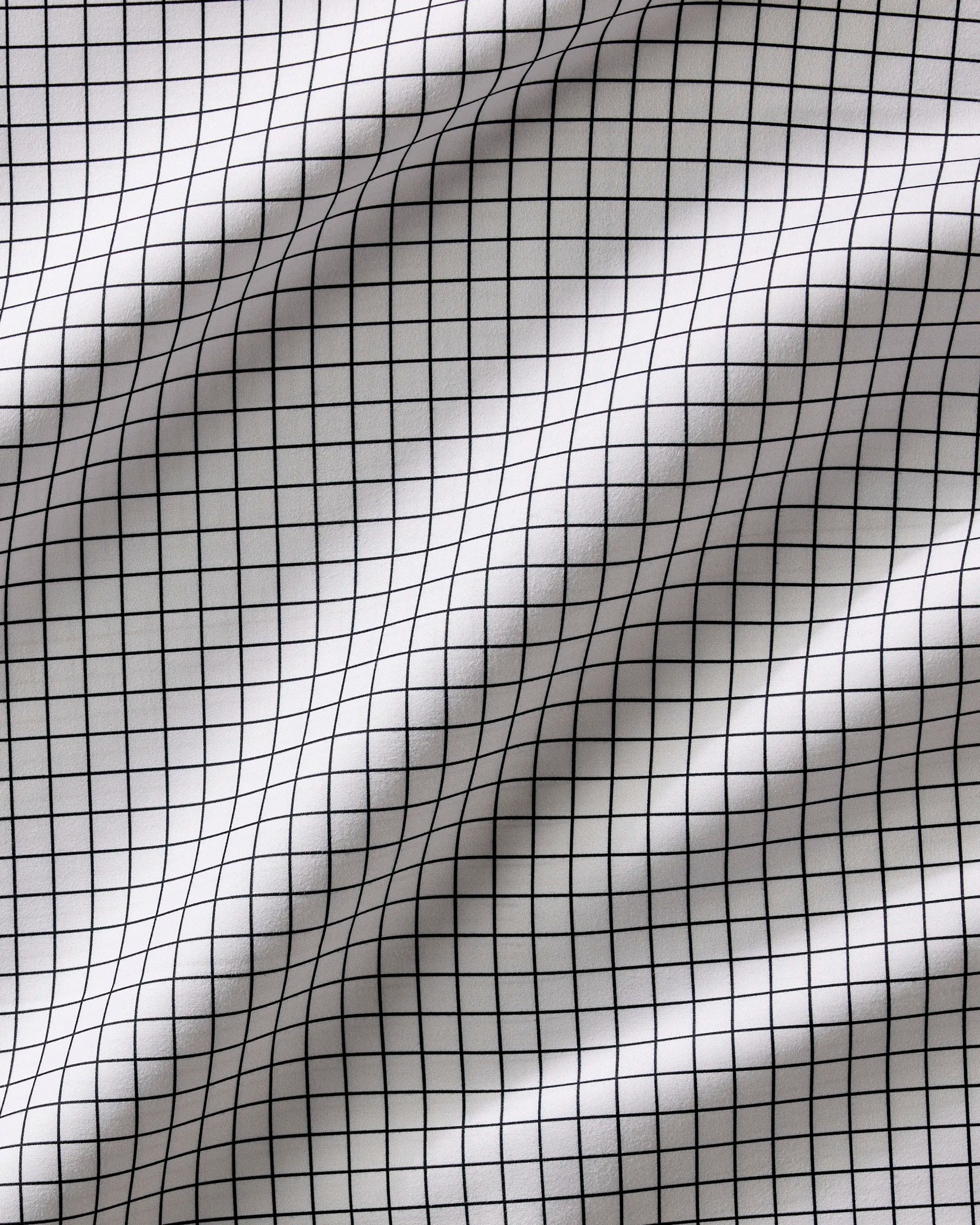Metro Grid by Geometry is a white fabric with a black grid of small, evenly spaced squares. Its gentle folds add dimension, making it perfect for reusable cloth napkins to enhance any dinner napkin set.