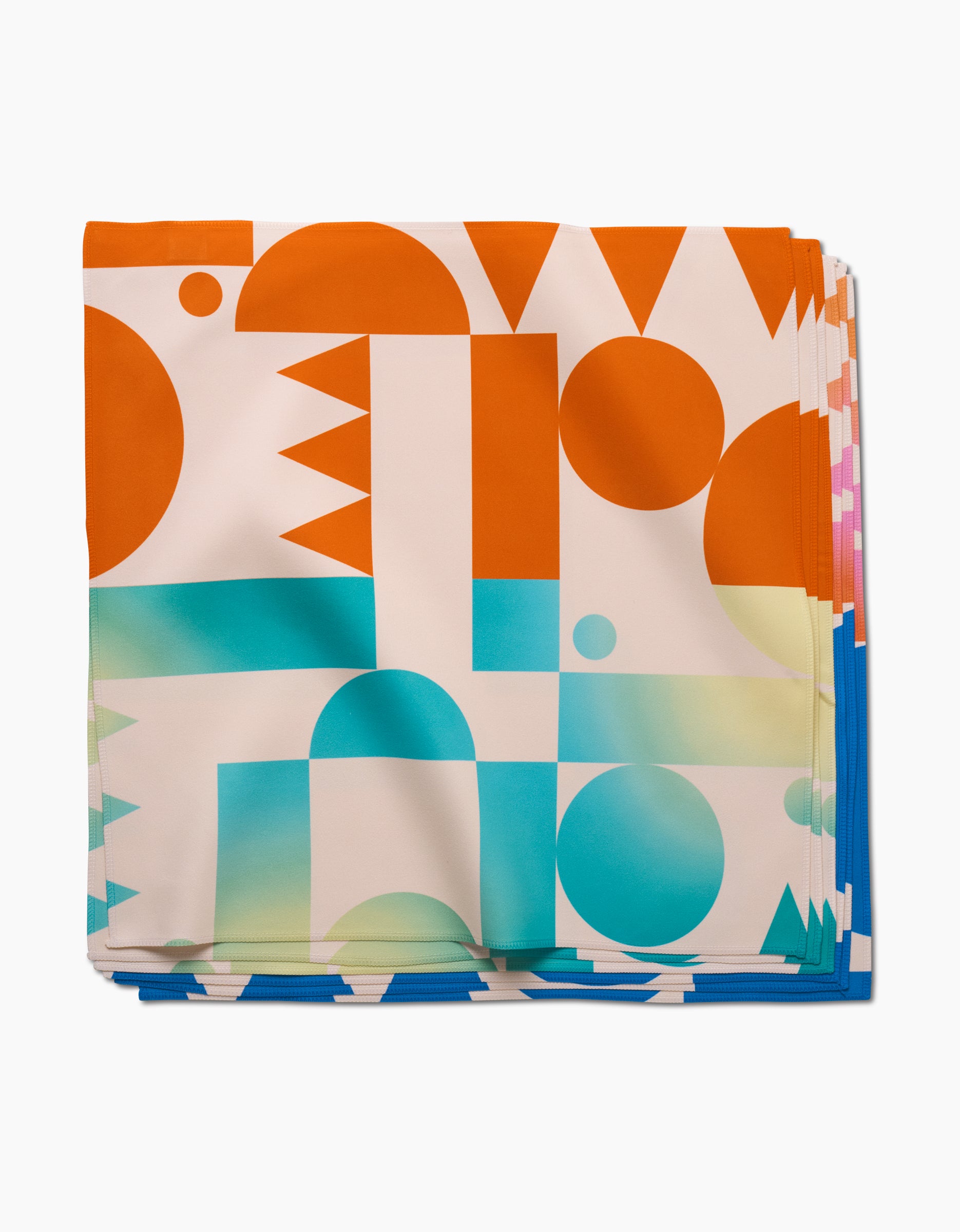 The GEOMETRY Moody Shapes dinner napkin set features folded Geosuede fabric with a bold, colorful geometric pattern of circles, triangles, and rectangles in orange, blue, teal, and white.