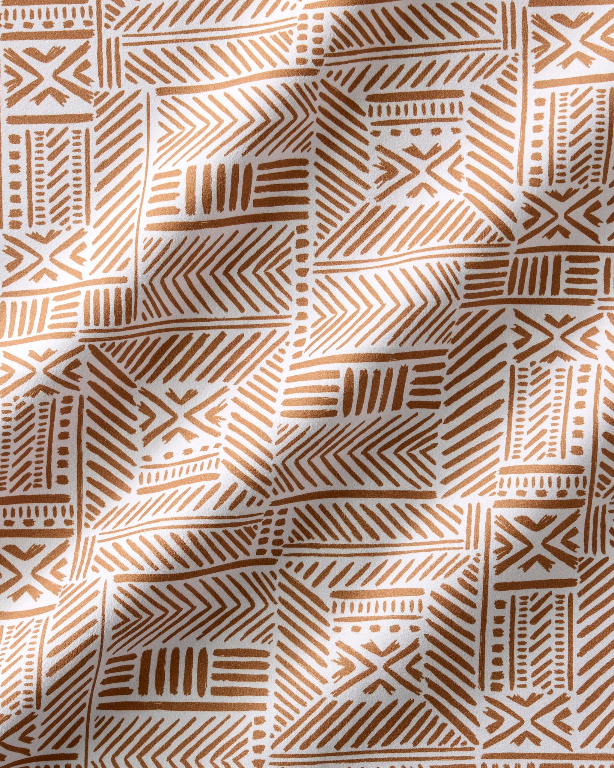 The Hufton Studio "Mud Cloth Natural" dinner napkin set features a brown geometric tribal pattern on white fabric with soft folds, ideal as eco-friendly napkins for sustainable, stylish dining.