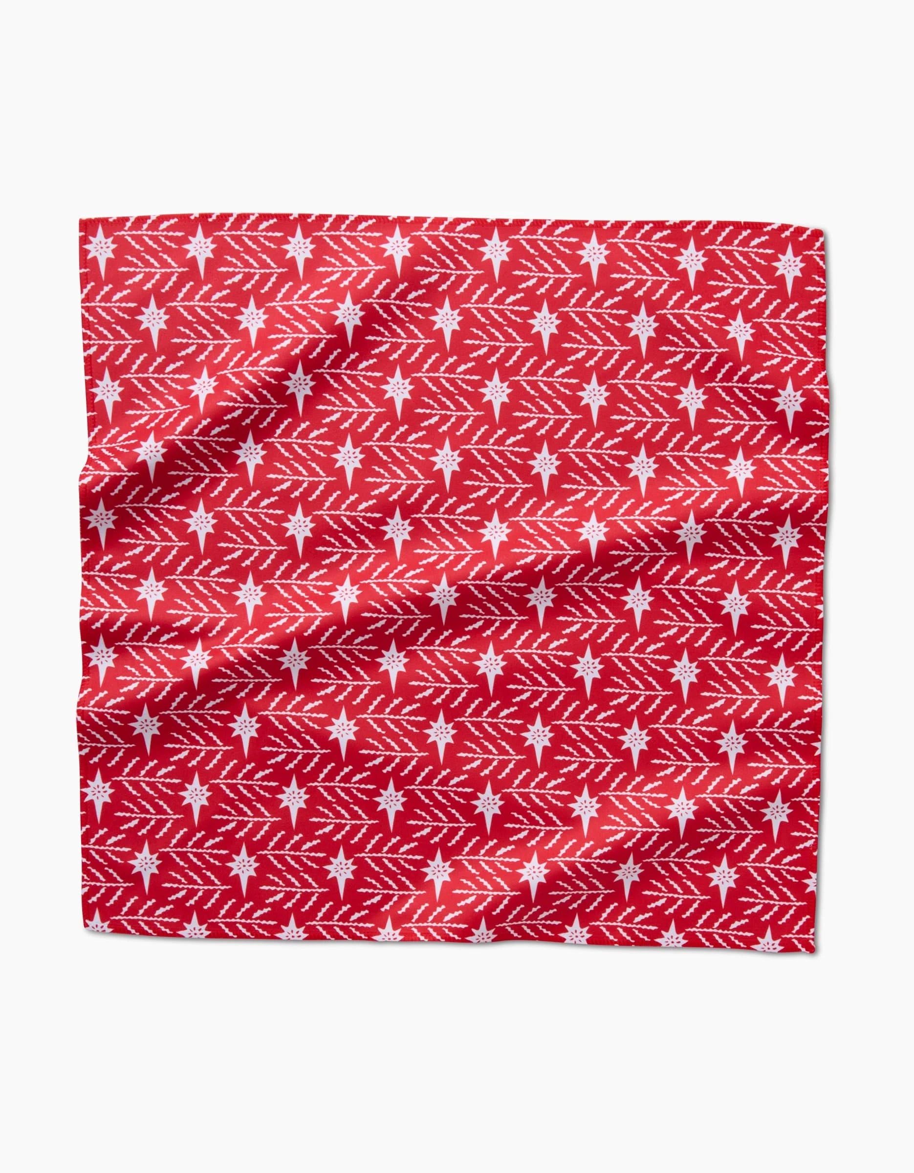 North Star by Roxy Marj is a red Geosuede fabric with a repeating pattern of white snowflakes and diagonal lines, evoking festive or winter themes. The fabric has a slightly wrinkled appearance.