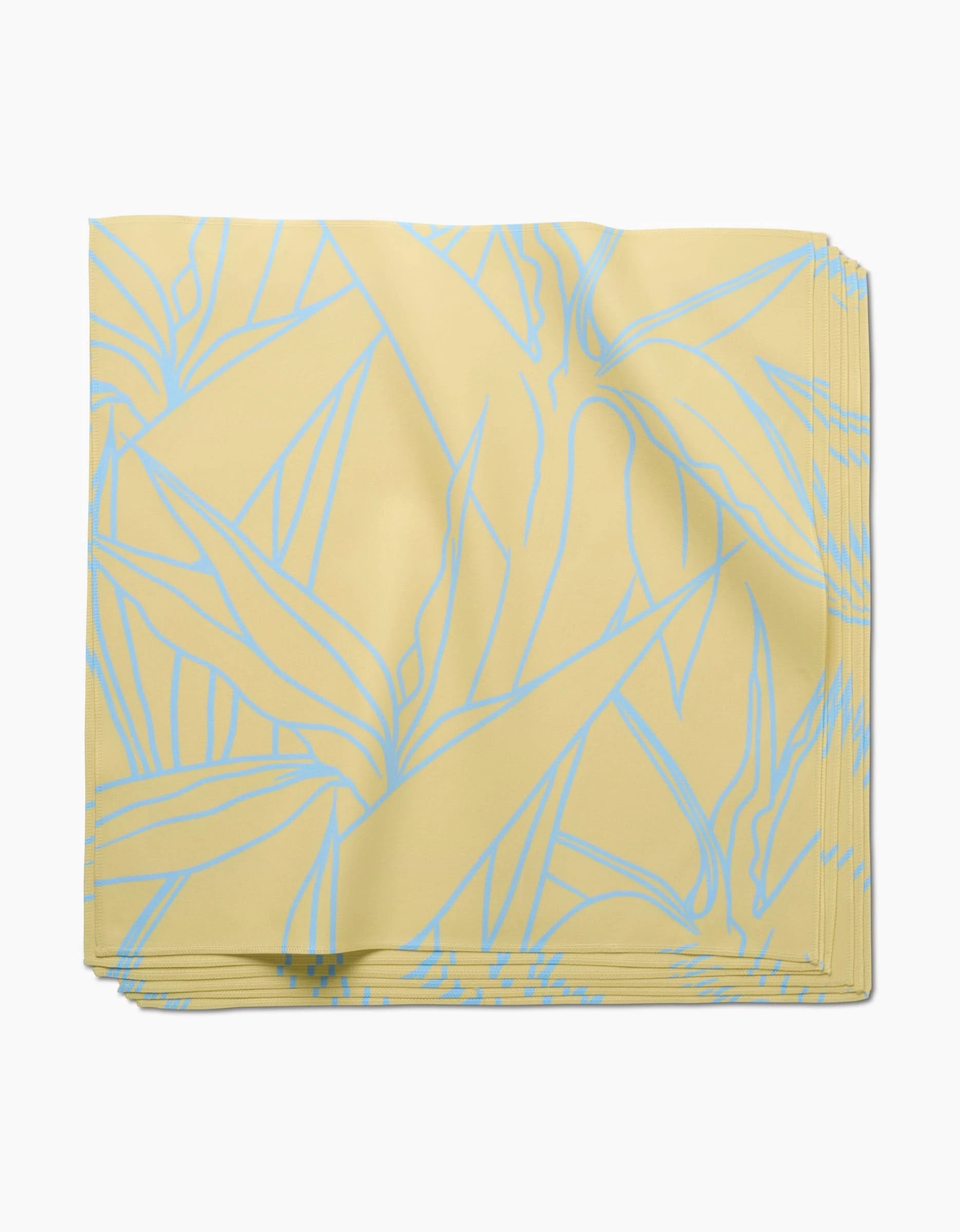 The GEOMETRY Paradise Blooms dinner napkin, crafted from soft Geosuede fabric, features a folded yellow square design with a light blue abstract leaf pattern and is shown on a white background.