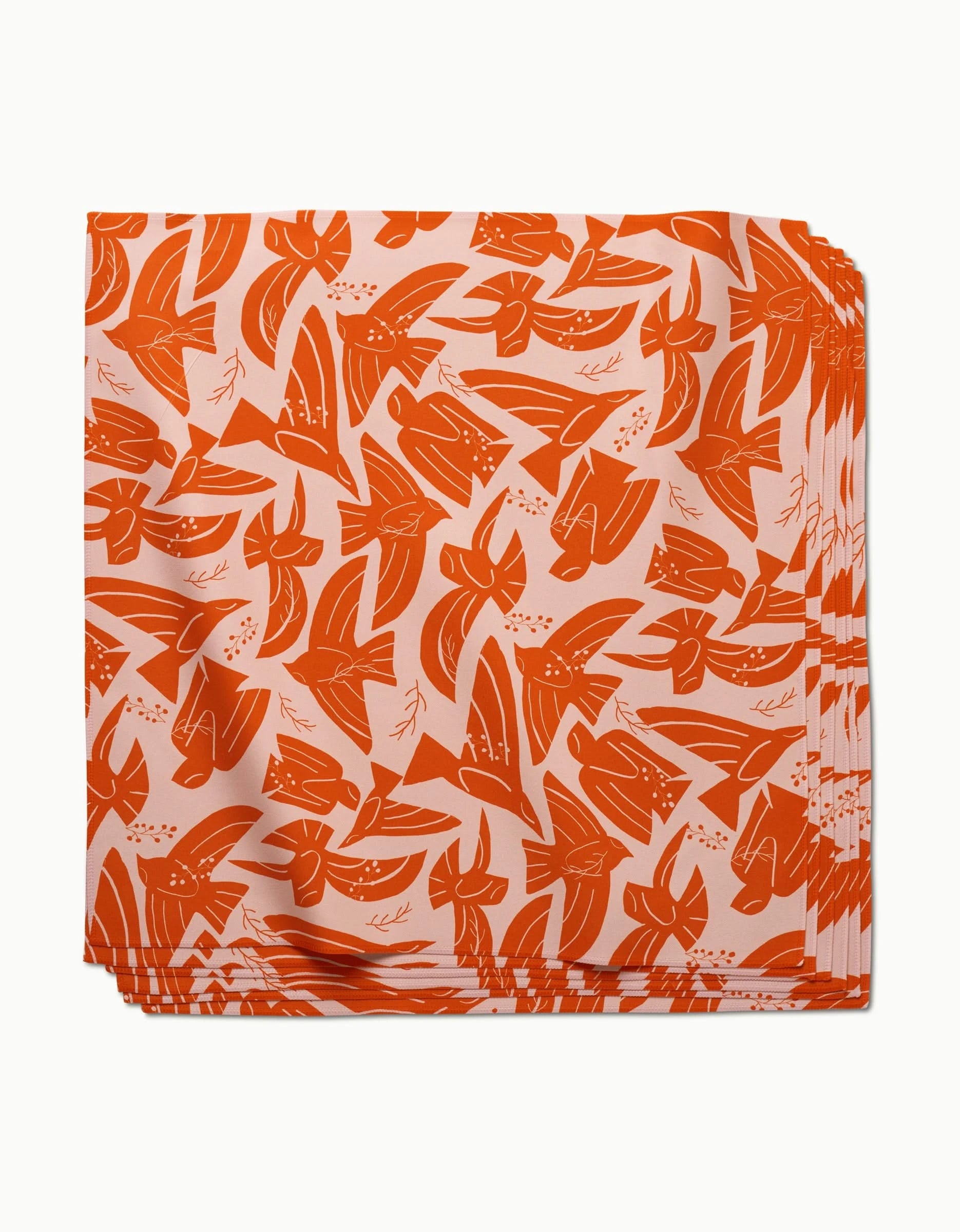 A stack of Ash Cascade Peace Bird absorbent dinner napkins, featuring an orange and white abstract floral pattern, is displayed against a white background.