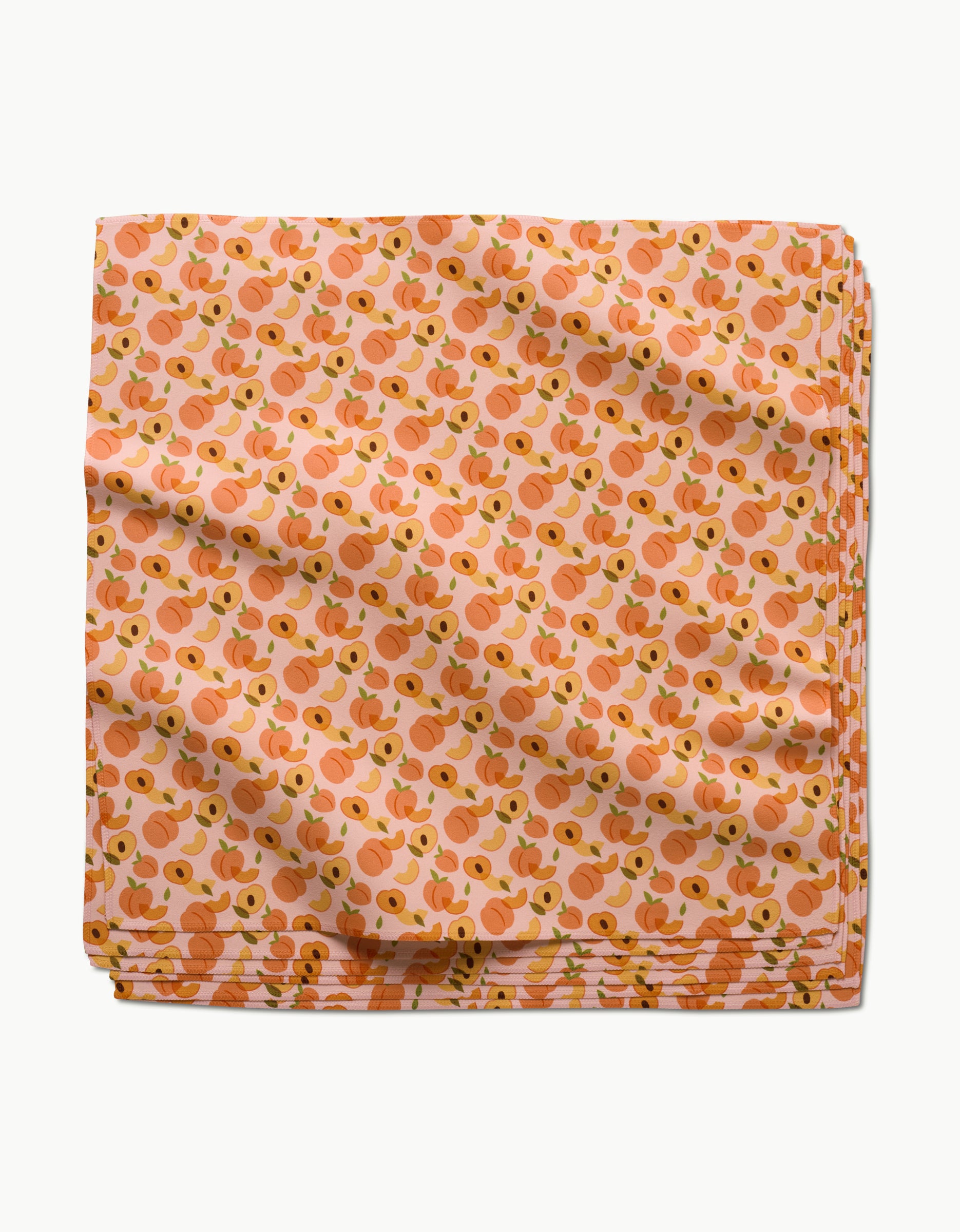 The GEOMETRY Peaches reusable napkin features a repeating peach and green leaf design on a light pink background, making it an eco-friendly choice for any dinner napkin set.