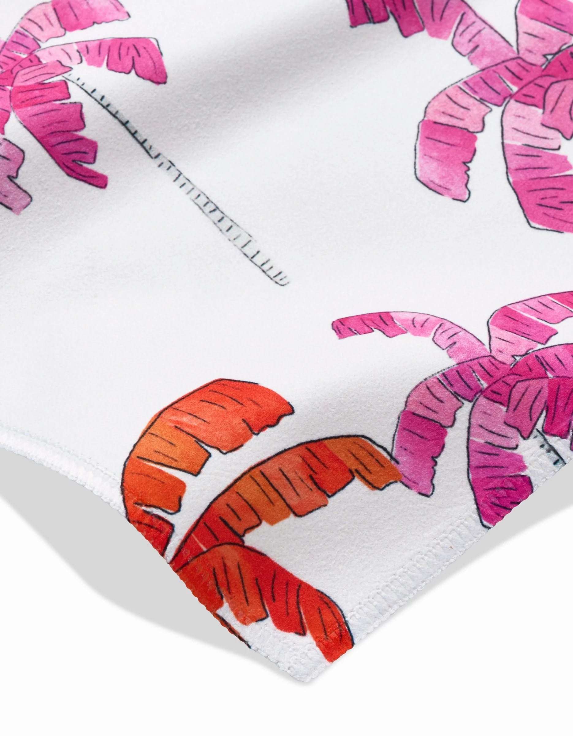 Close-up of GEOMETRYs Pink Palms dinner napkins in white Geosuede fabric, featuring a colorful tropical palm leaf print in pink, red, and orange. Soft texture, visible stitching, and made from recycled materials.
