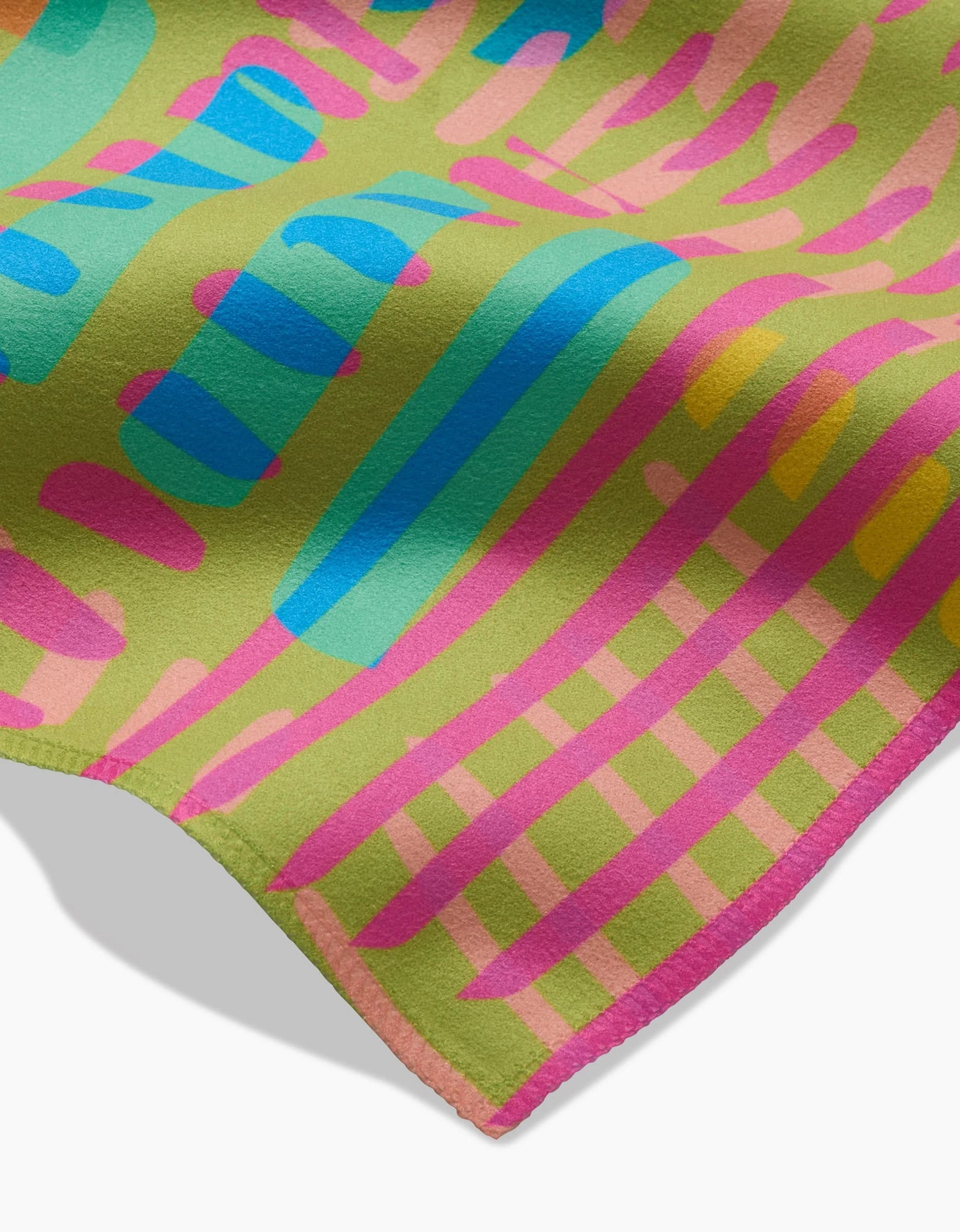 A close-up of the Positive Vibes dinner napkin set by Sareka Unique, featuring colorful abstract stripes and shapes on a light green Geosuede fabric made from recycled materials with soft texture and visible stitched edges.
