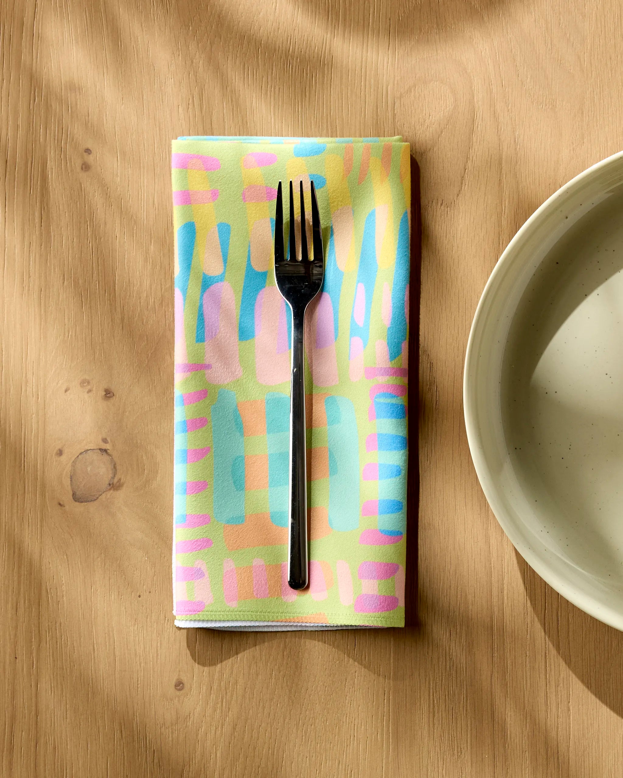 A fork resting on a Positive Vibes napkin by Sareka Unique.