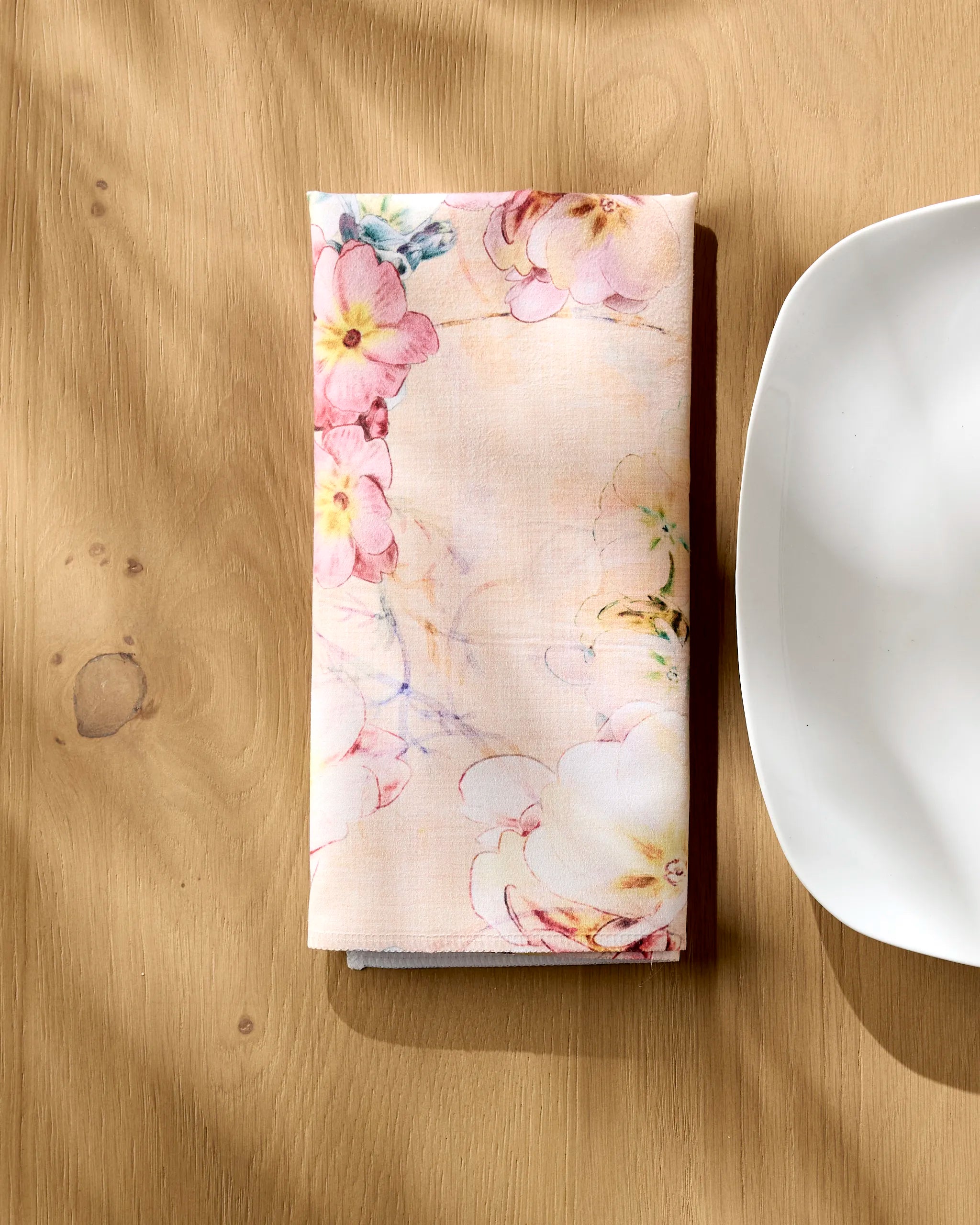 A Primroses dinner napkin by Pascale Dilger and a plate are set on the table.