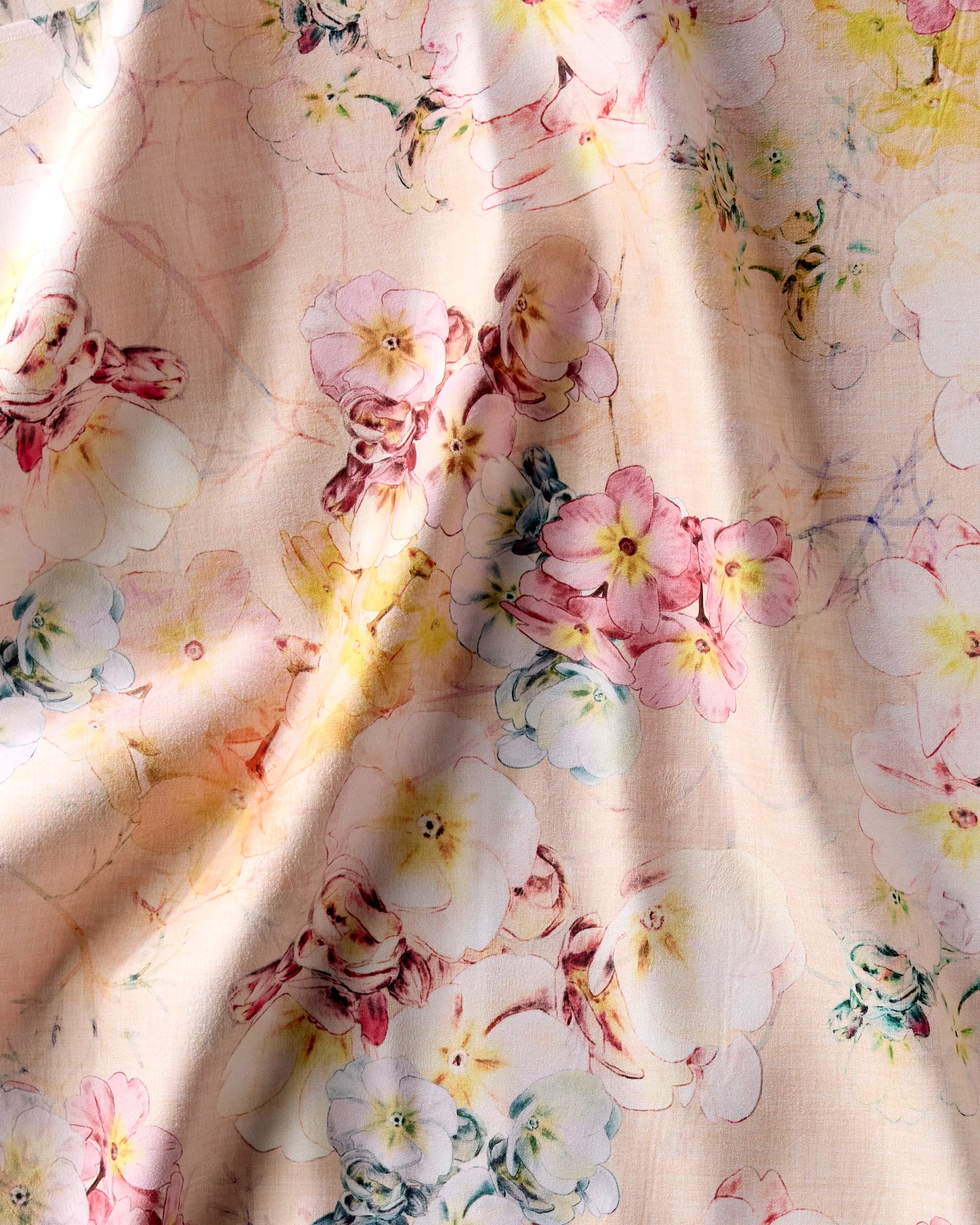 Primroses by Pascale Dilger features soft pink fabric adorned with clusters of pink, yellow, and white flowers. Its gentle wrinkles add charm, making it perfect for reusable cloth napkins or enhancing any dinner napkin set.