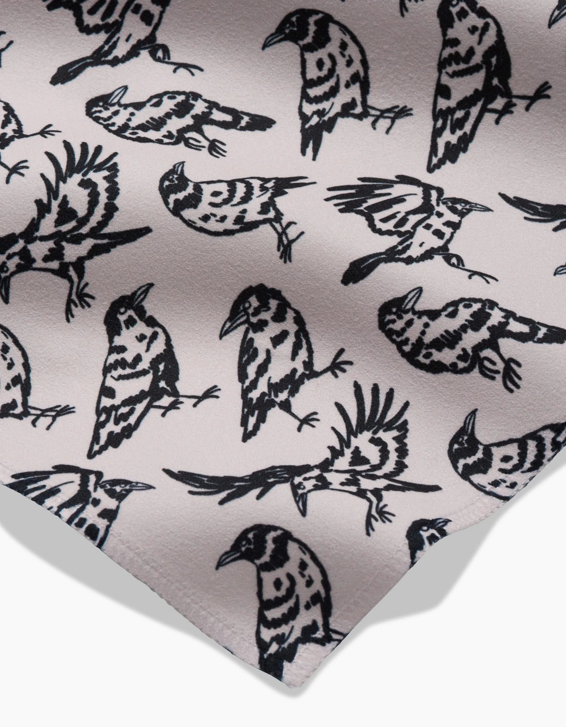 A close-up of Kayla Anns Raven napkins, featuring absorbent fabric with a repeating black-and-white bird pattern in simple, bold lines against a light background.