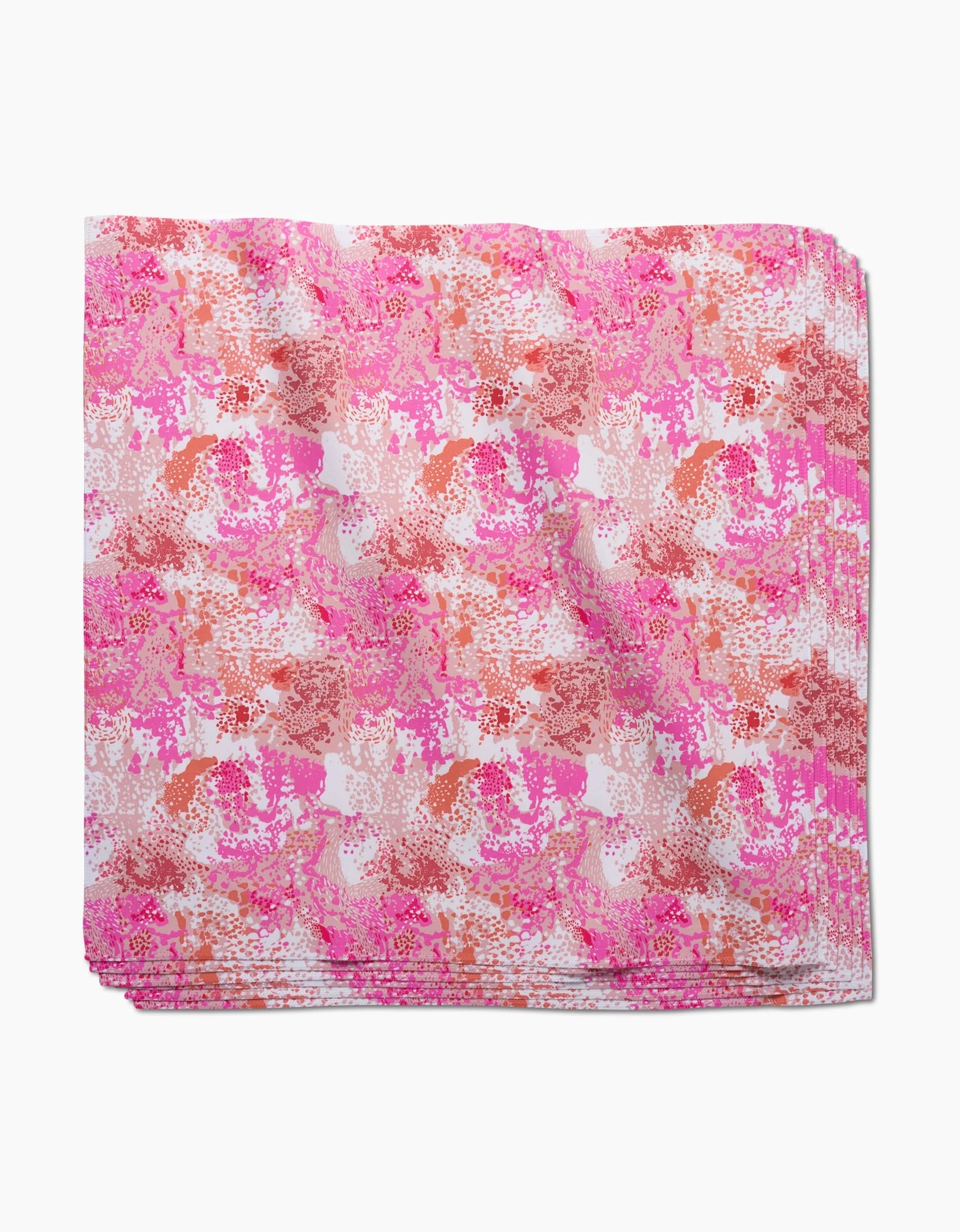 A stack of Elisabeth Wing Rawhide dinner napkins made from Geosuede fabric, featuring a pink and red abstract floral pattern on white, placed against a plain white surface.