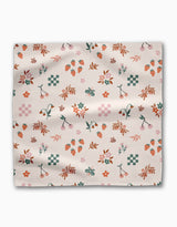 The Russet Meadow square scarf by Charlie Rowan Designs features a cream background with strawberries, cherries, bees, florals, leaves, and pink geometric shapes in red, orange, green, and pink on soft Geosuede fabric.