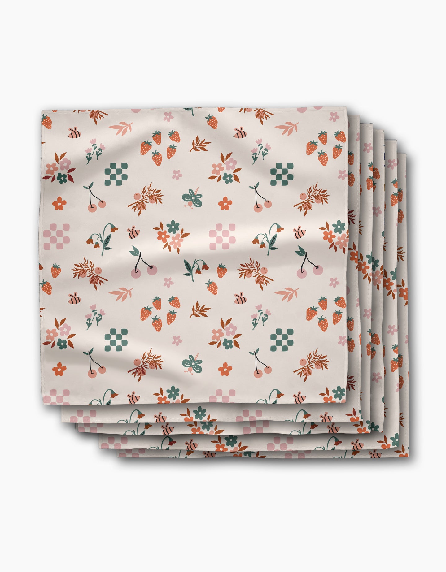 A stack of four Russet Meadow dinner napkins by Charlie Rowan Designs, made from soft Geosuede fabric, featuring a colorful pattern of flowers, leaves, strawberries, cherries, and geometric shapes on a white background.