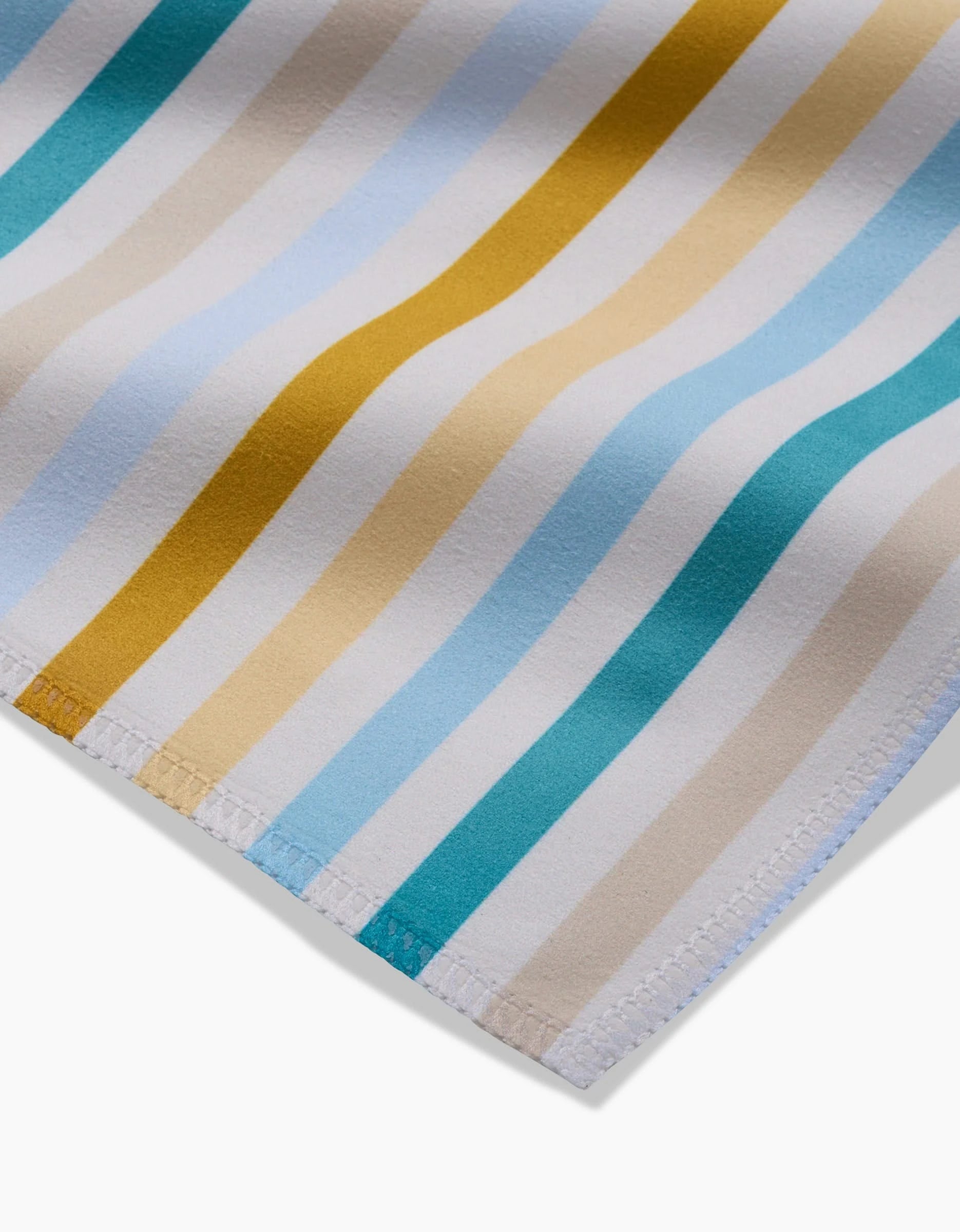 Close-up of GEOMETRY’s Seaside Sunshine: Geosuede fabric features diagonal stripes in white, beige, light blue, and mustard yellow with stitched edges, showcasing this eco-friendly material made from recycled materials.