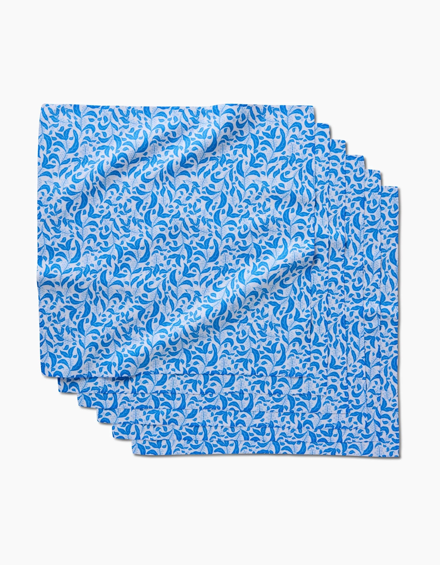 The Snowberry Dinner Napkin Set by Danelys Sidron features a folded blue and white wavy leaf-like pattern, made from recycled materials, displayed against a white background.