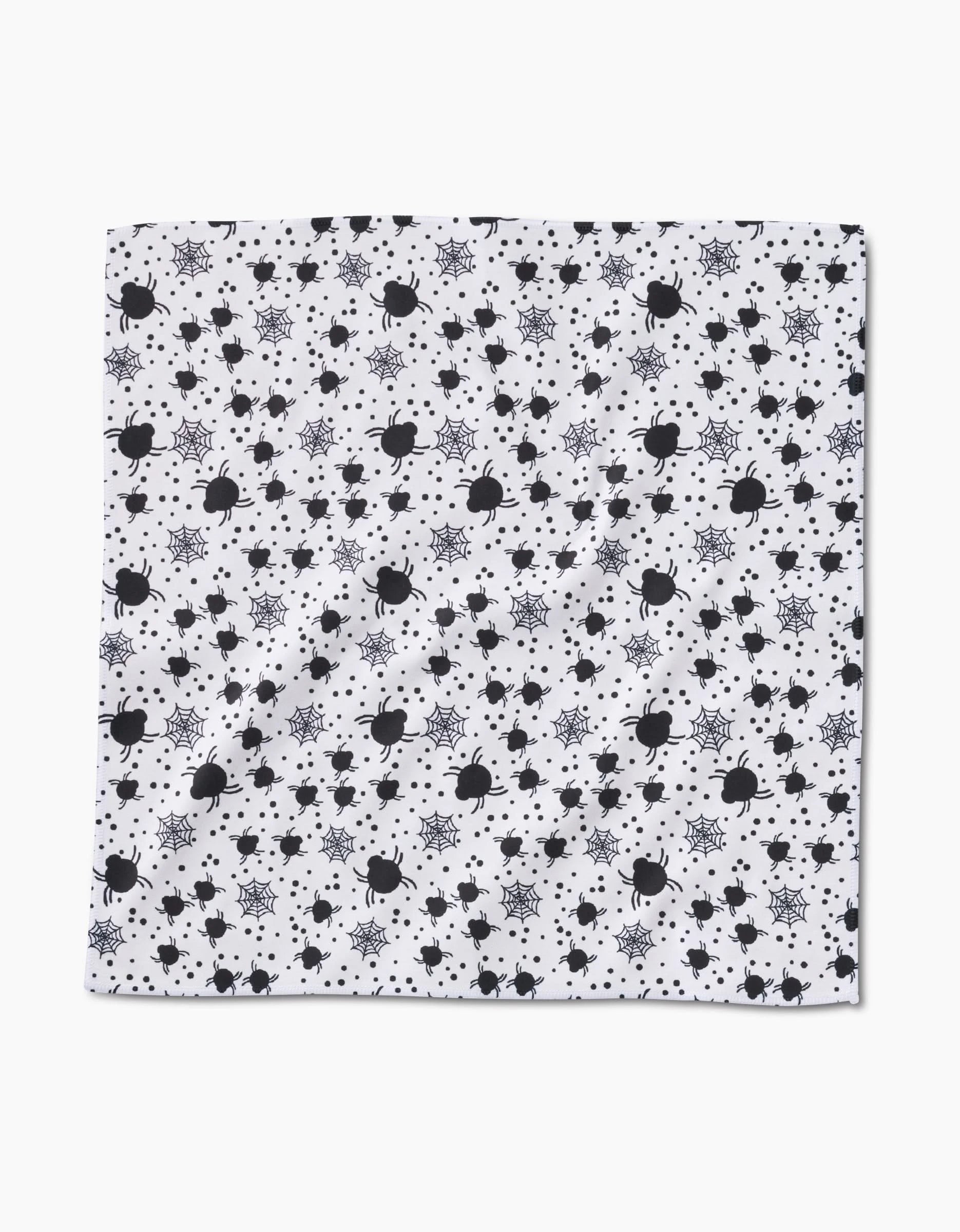 A white Geosuede square from Charlie Rowan Designs, featuring the playful Spiders For Days pattern—black bombs, gray explosions, and stars—makes a perfect recycled napkin for a standout dinner set.