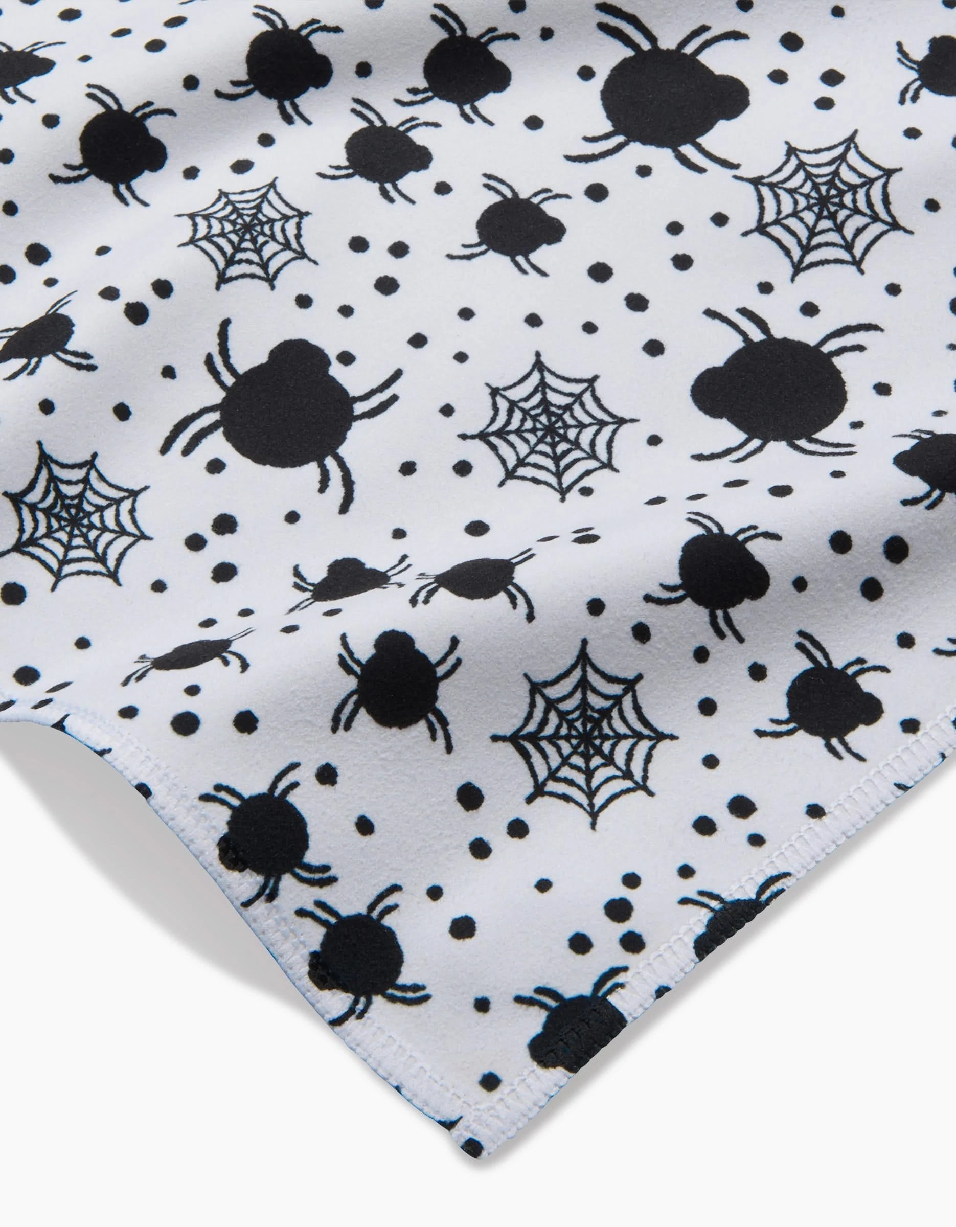 The Spiders For Days dinner napkins by Charlie Rowan Designs feature recycled white Geosuede fabric with a playful pattern of black spiders, webs, and dots—perfect for Halloween, with evenly spaced motifs and a visible fabric edge.