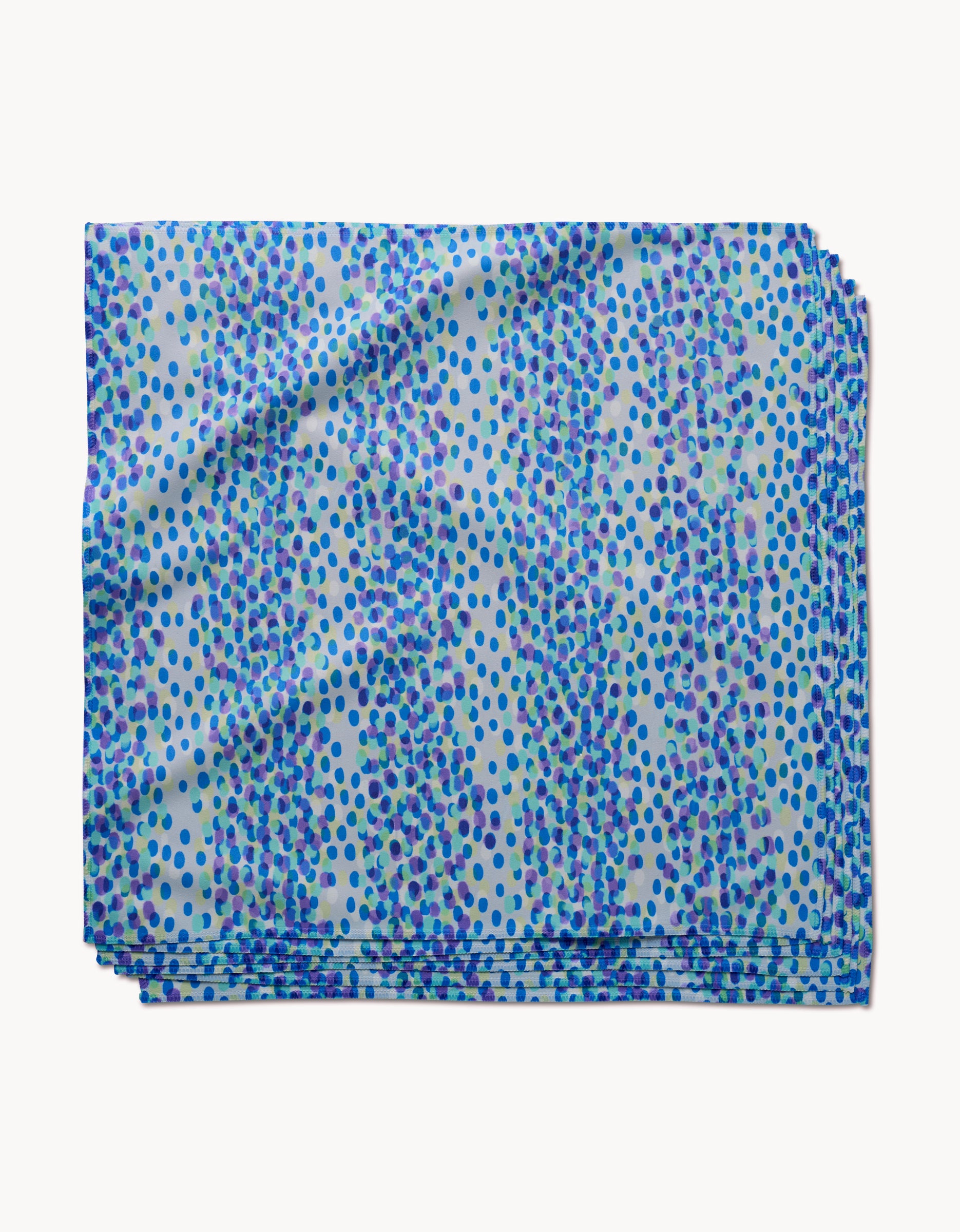 The GEOMETRY Spotty Summer is a folded absorbent cloth napkin with small blue and purple dots on a light blue background, displayed against a white surface.