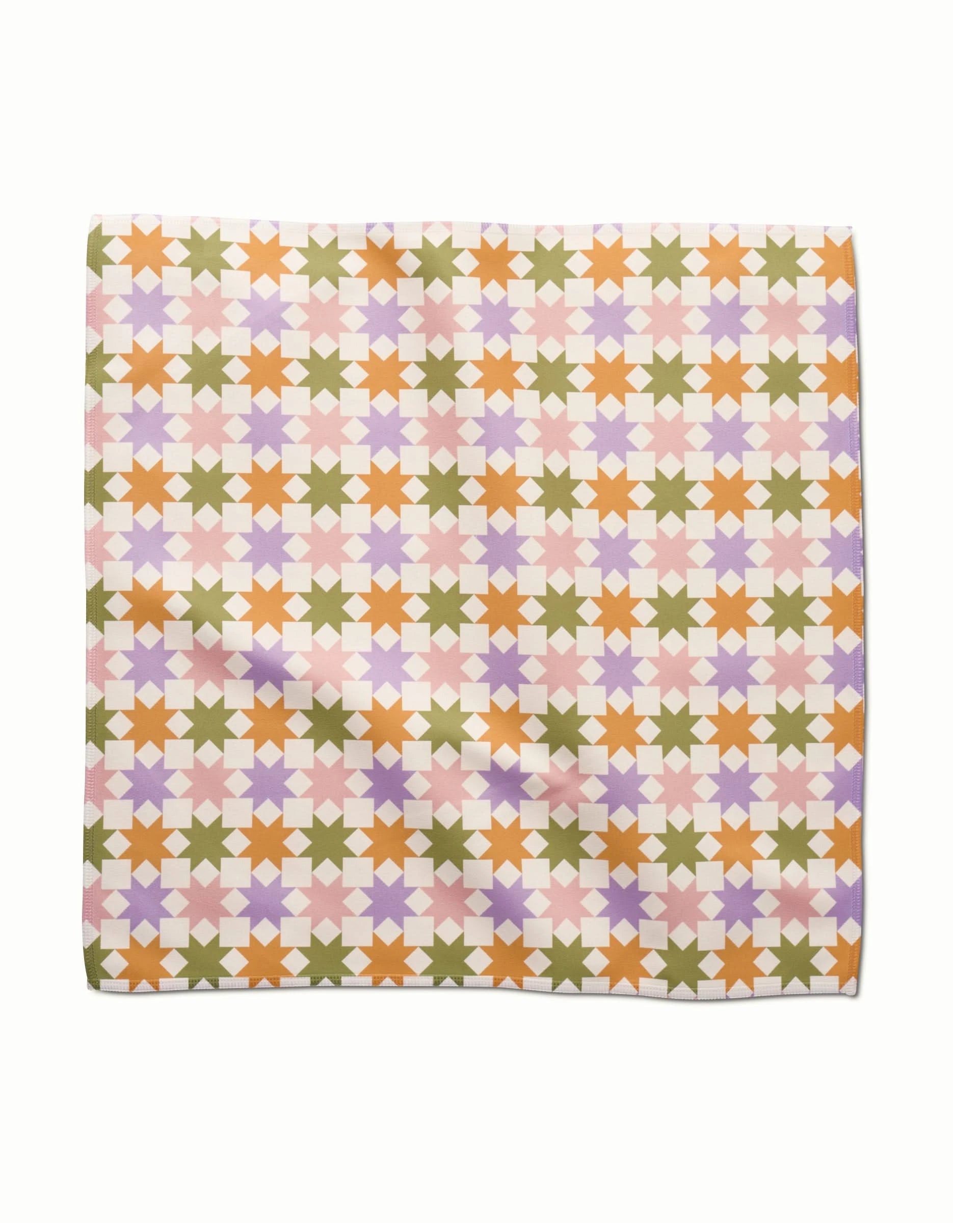 The Kayla Ann Spring Quilt features folded Geosuede fabric with a geometric star pattern in orange, pink, purple, and olive green on a light background arranged in a repeating grid.