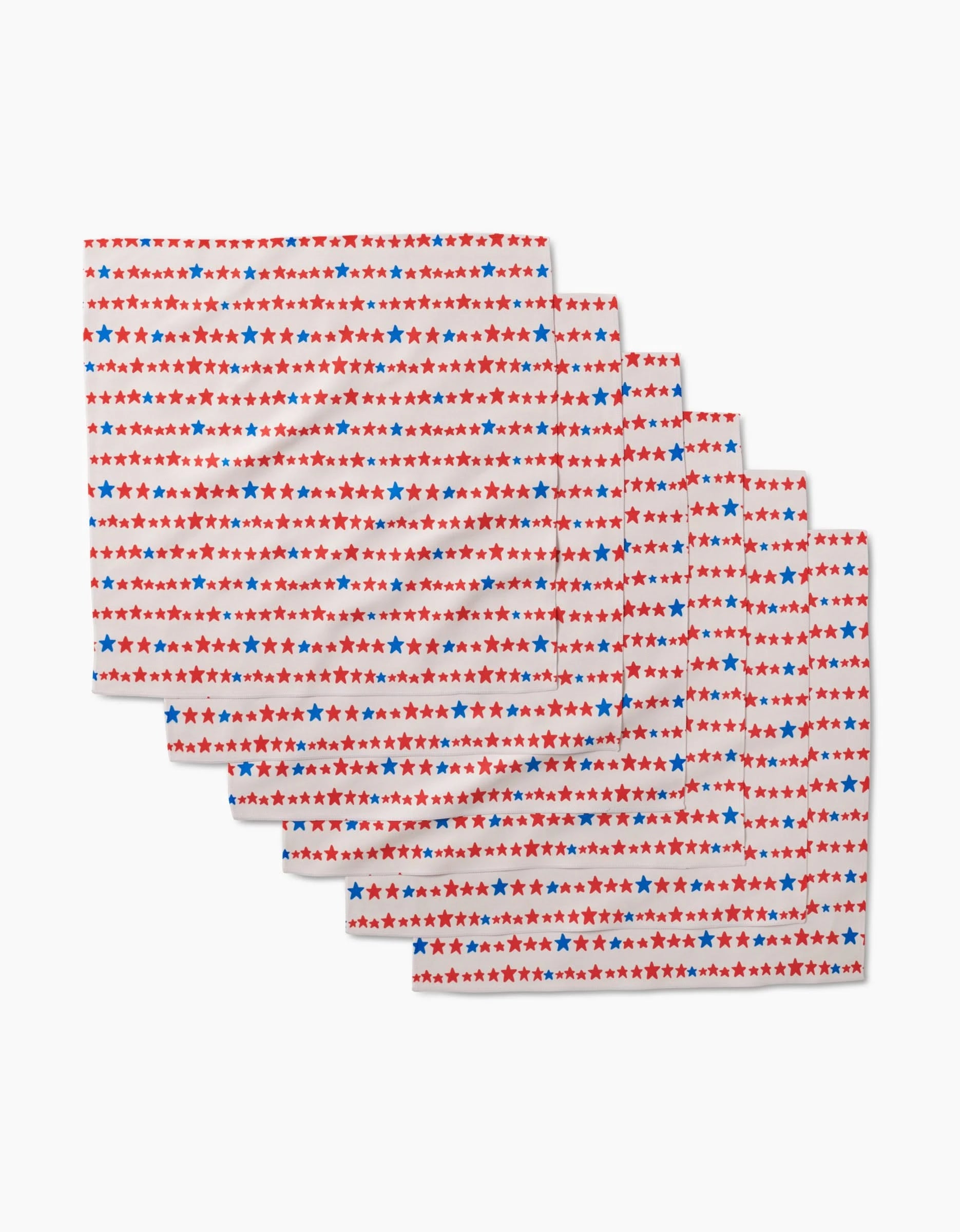 Six Starry Stripes rectangular placemats by Kayla Ann, made from recycled materials, feature a white background with repeating red and blue star rows. The set of six is neatly stacked and slightly fanned out.