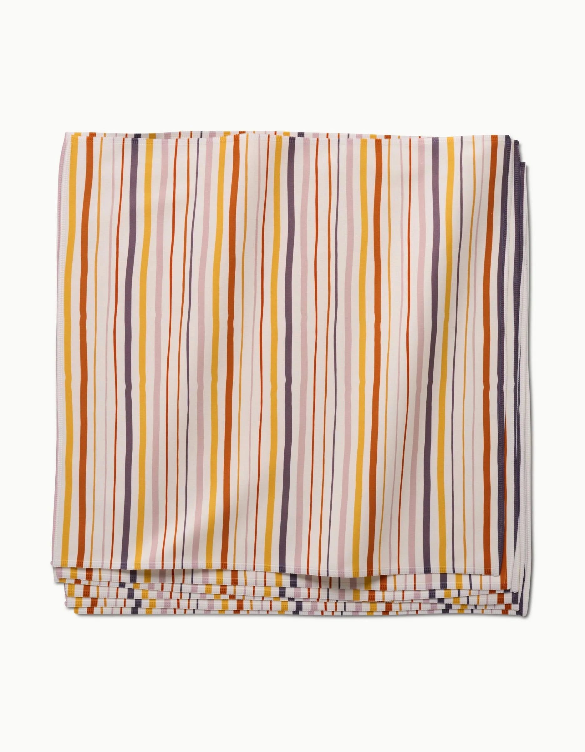 The GEOMETRY Stripe Season dinner napkin, crafted from folded Geosuede fabric, features vertical orange, yellow, brown, and light gray stripes on white and is displayed against a plain white surface.