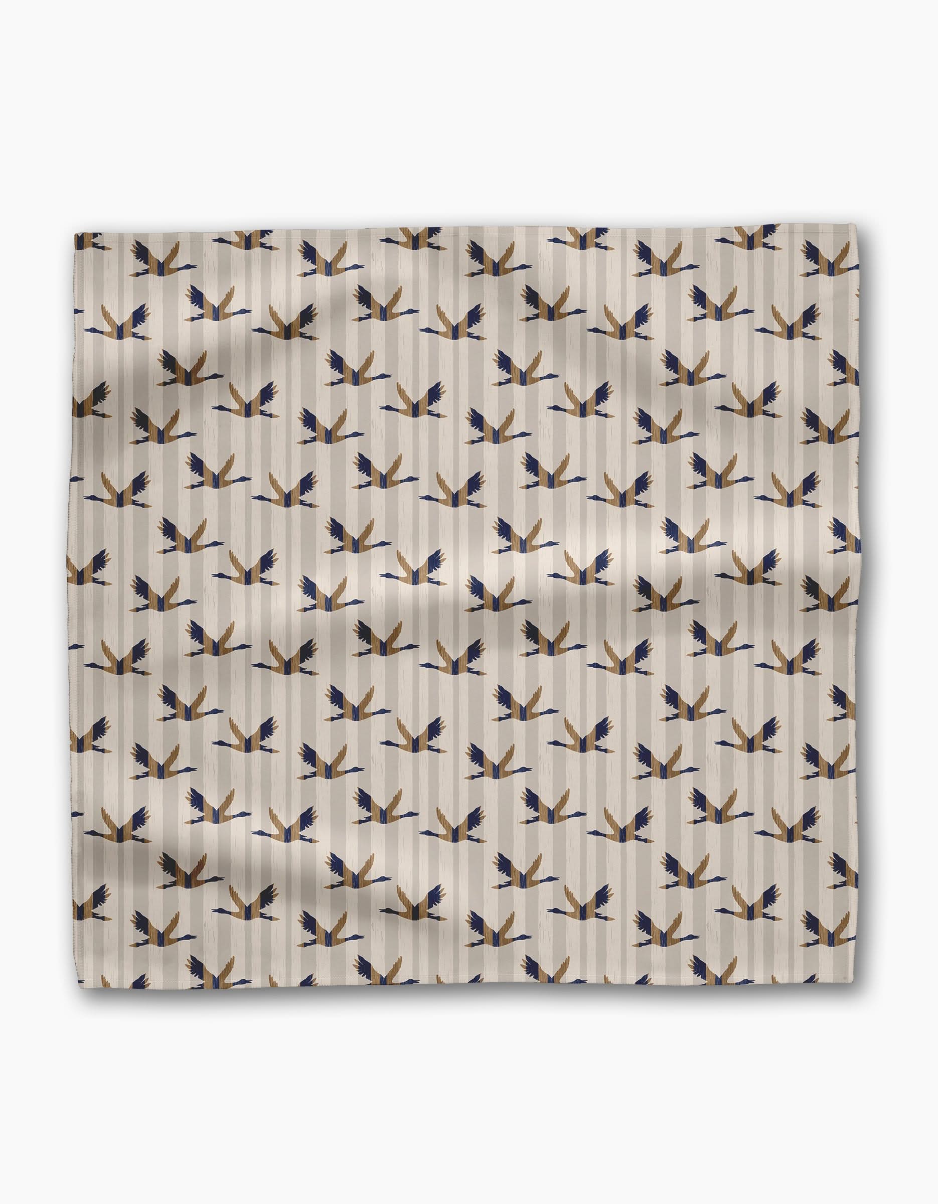 Striped Nautical Birds by Geometry is a beige Geosuede fabric featuring rows of stylized blue and gold birds in flight on a subtle striped background, ideal for dinner napkins with visible folds and shadows.