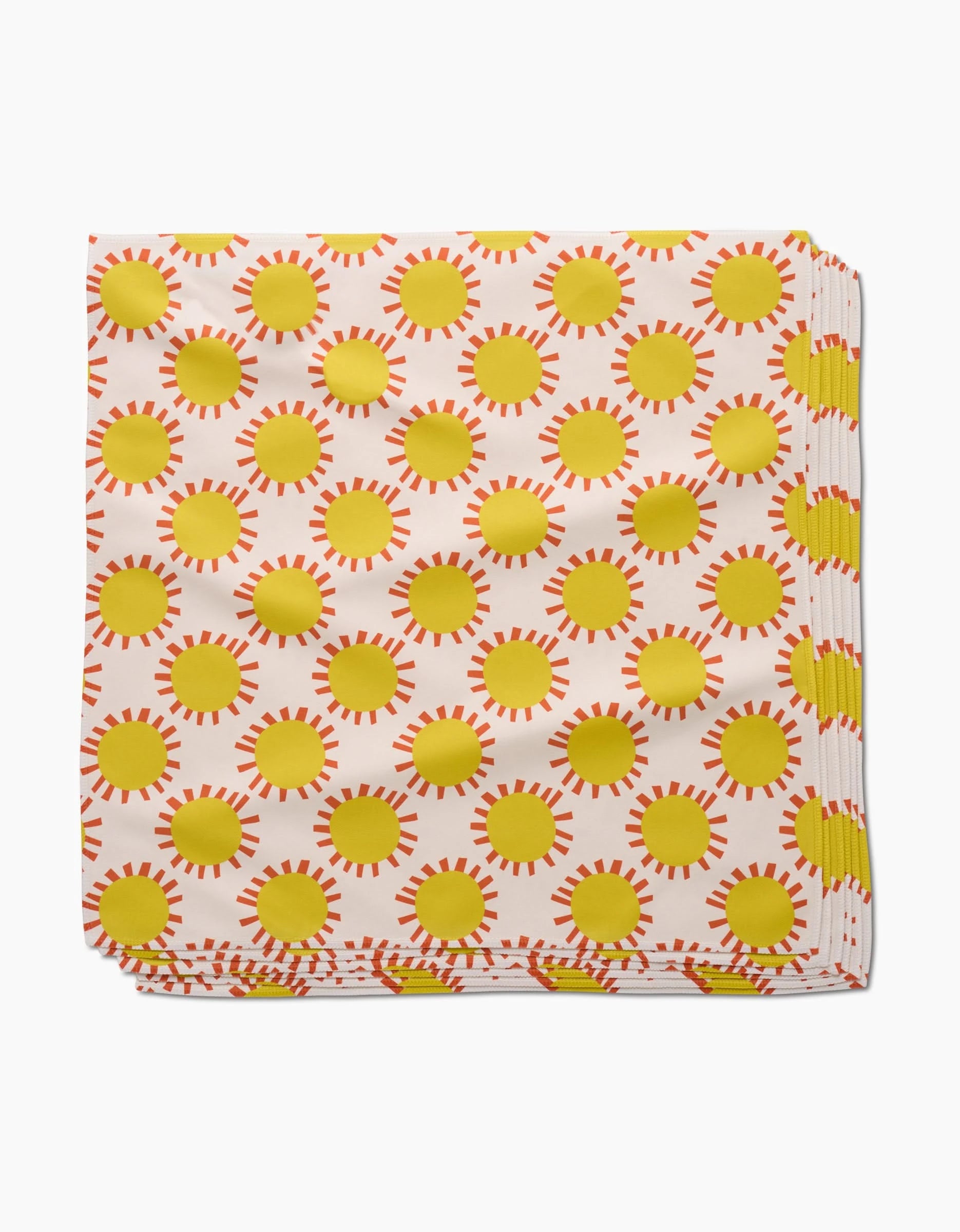 The Lizzie Clark Sunny Day Dinner Napkin is folded, made from Geosuede fabric, and features a white design with a repeating pattern of yellow suns and orange rays.