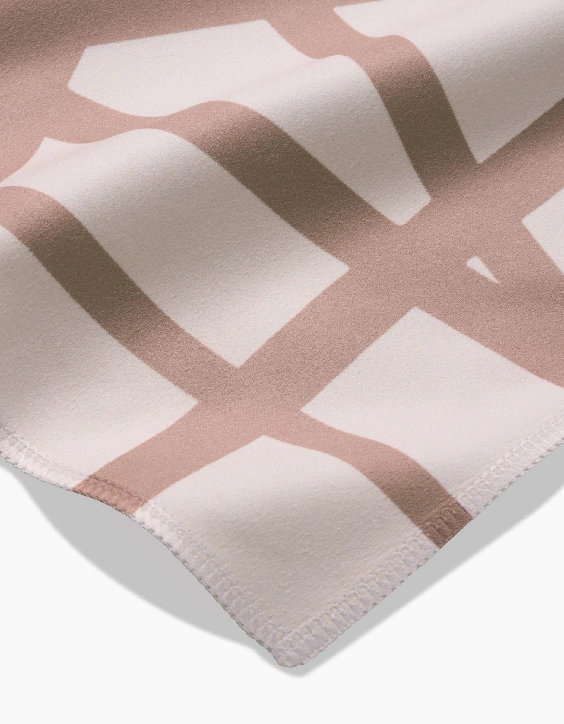 A close-up of Sunny Stripes by GEOMETRY, featuring soft Geosuede fabric with a beige and white geometric design, stitched edges, and shadows on a plain background. Made from recycled materials for eco-friendly style.