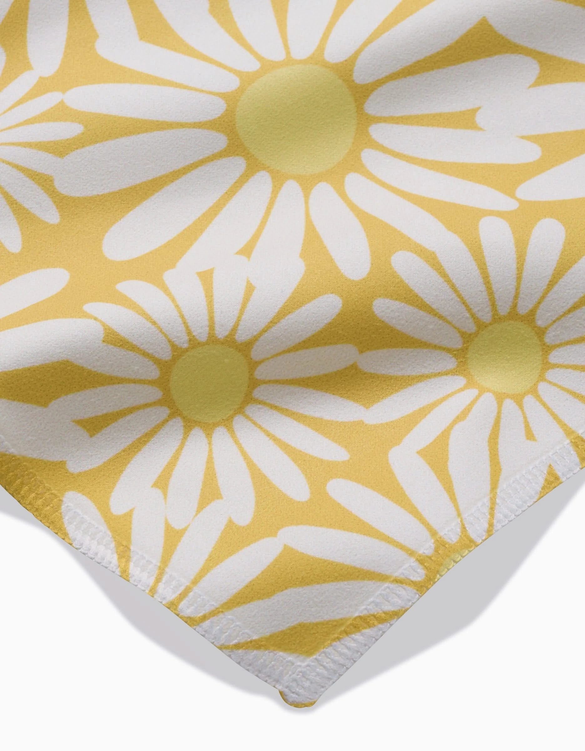 The Sunshine Meadow dinner napkin set by Rebecca Bobko features yellow Geosuede fabric with large white daisies, visible edge stitching, and is crafted from post-consumer recycled materials.