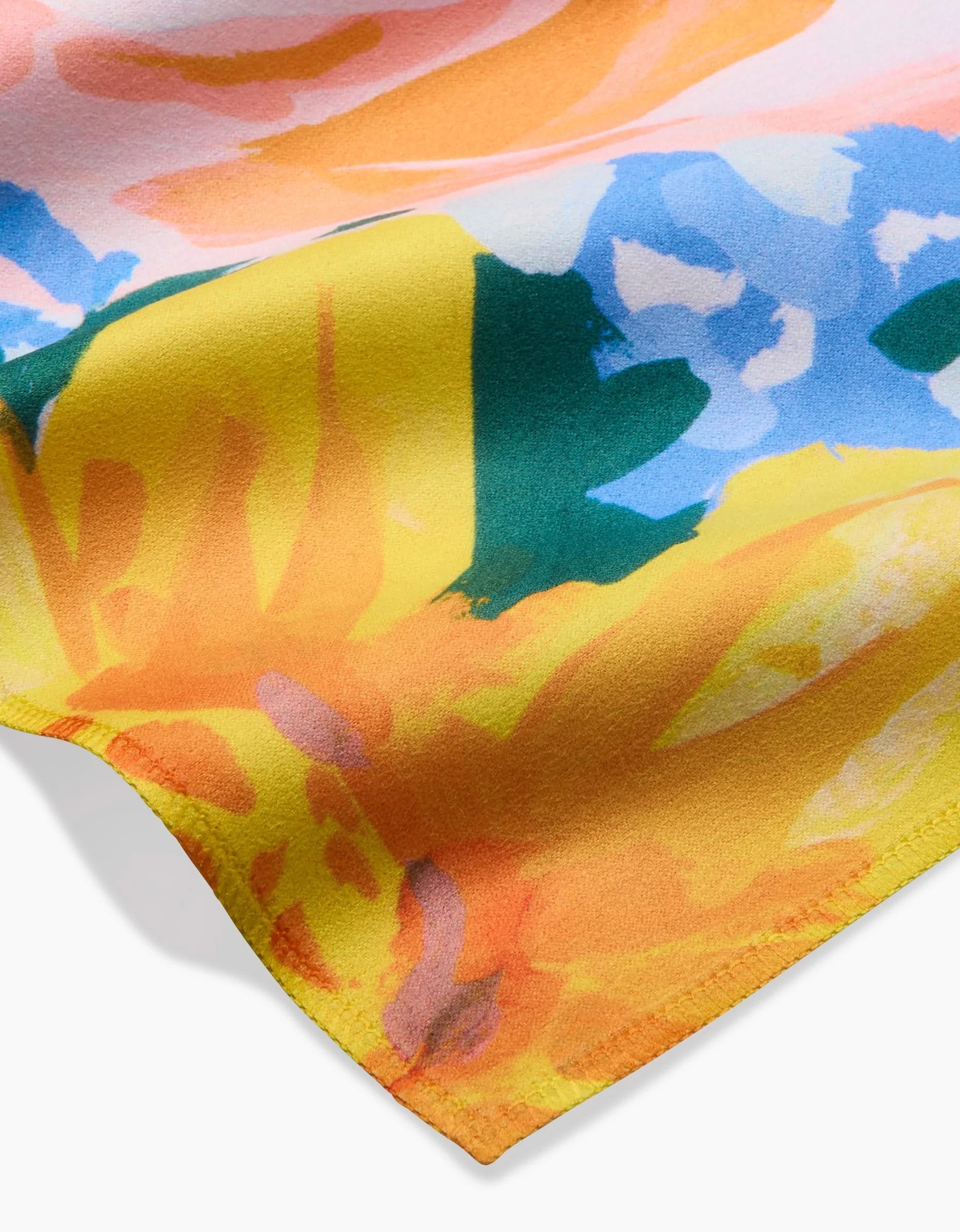 A close-up of Suzzy by Ania Zwara Art, showcasing bold yellow, green, blue, pink, and peach floral hues on soft Geosuede fabric with visible edge stitching.