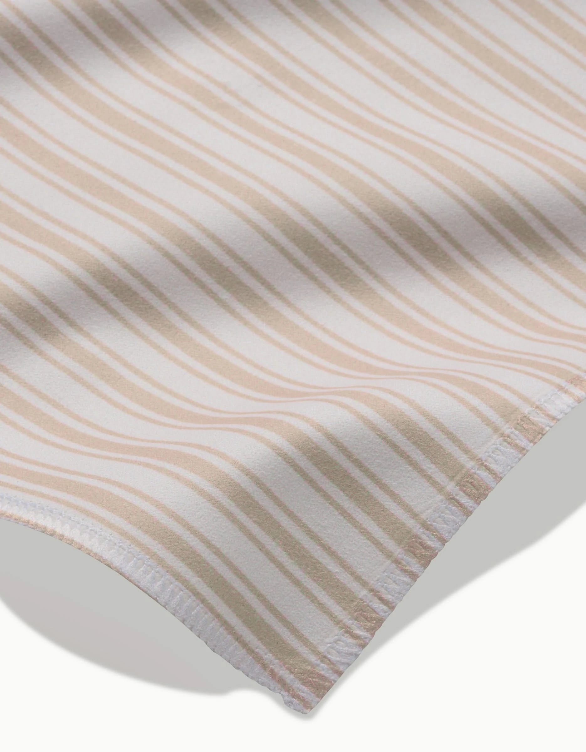 Close-up of Sweet Boho by Hufton Studio: a white fabric with diagonal beige stripes and a neatly finished hem. This soft, lightweight material is part of our reusable dinner napkins—an eco-friendly choice for your table.