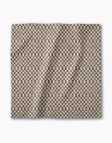 The Geometry Tavern is a square dinner napkin with a small brown and white checkerboard pattern. Eco-friendly and neatly folded, it’s showcased against a plain white background.
