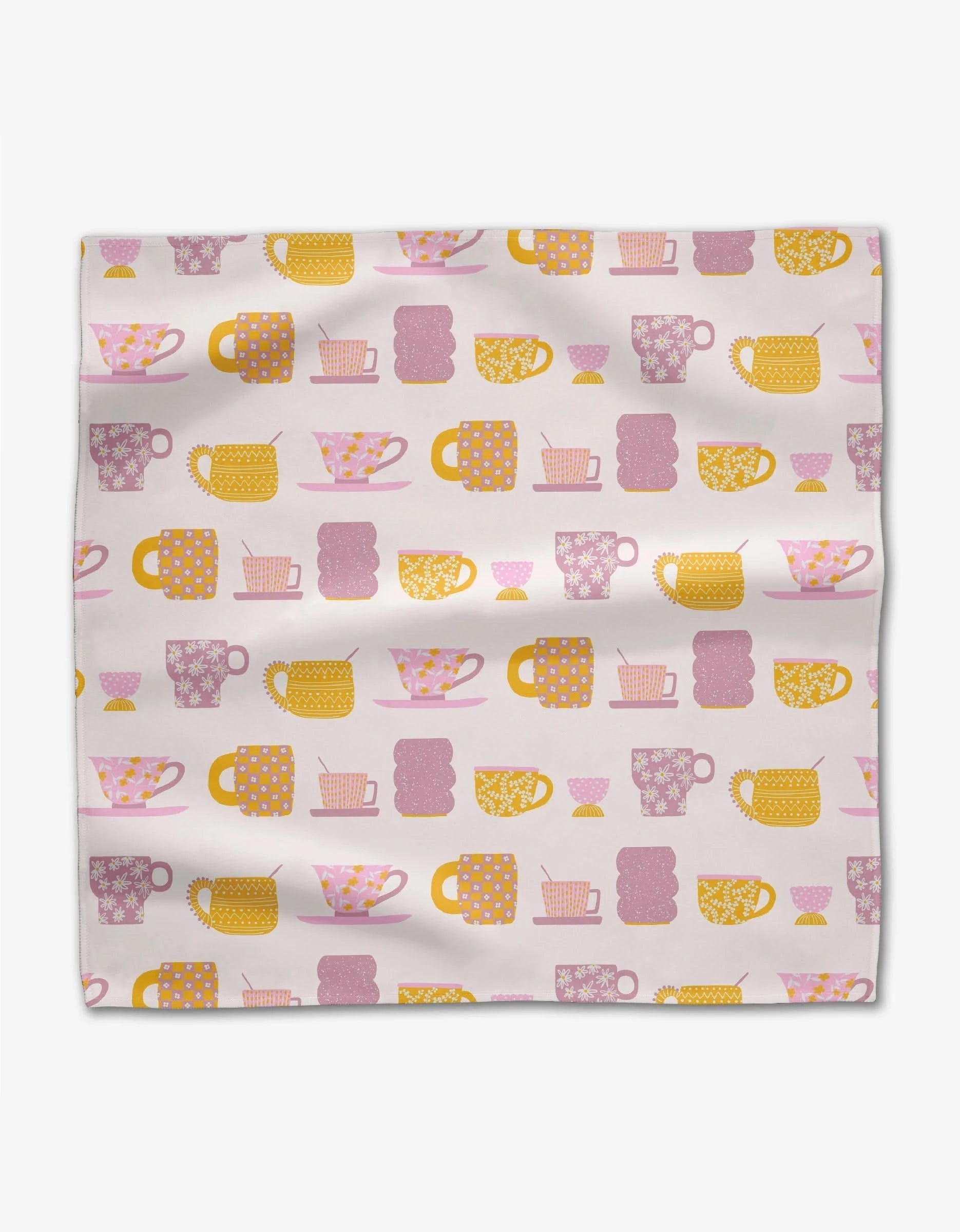 The GEOMETRY Tenderhearted is a square dinner napkin made from Geosuede fabric, showcasing a grid pattern of pink, yellow, and orange teacups, mugs, and teapots on a light background with a slightly wrinkled look.