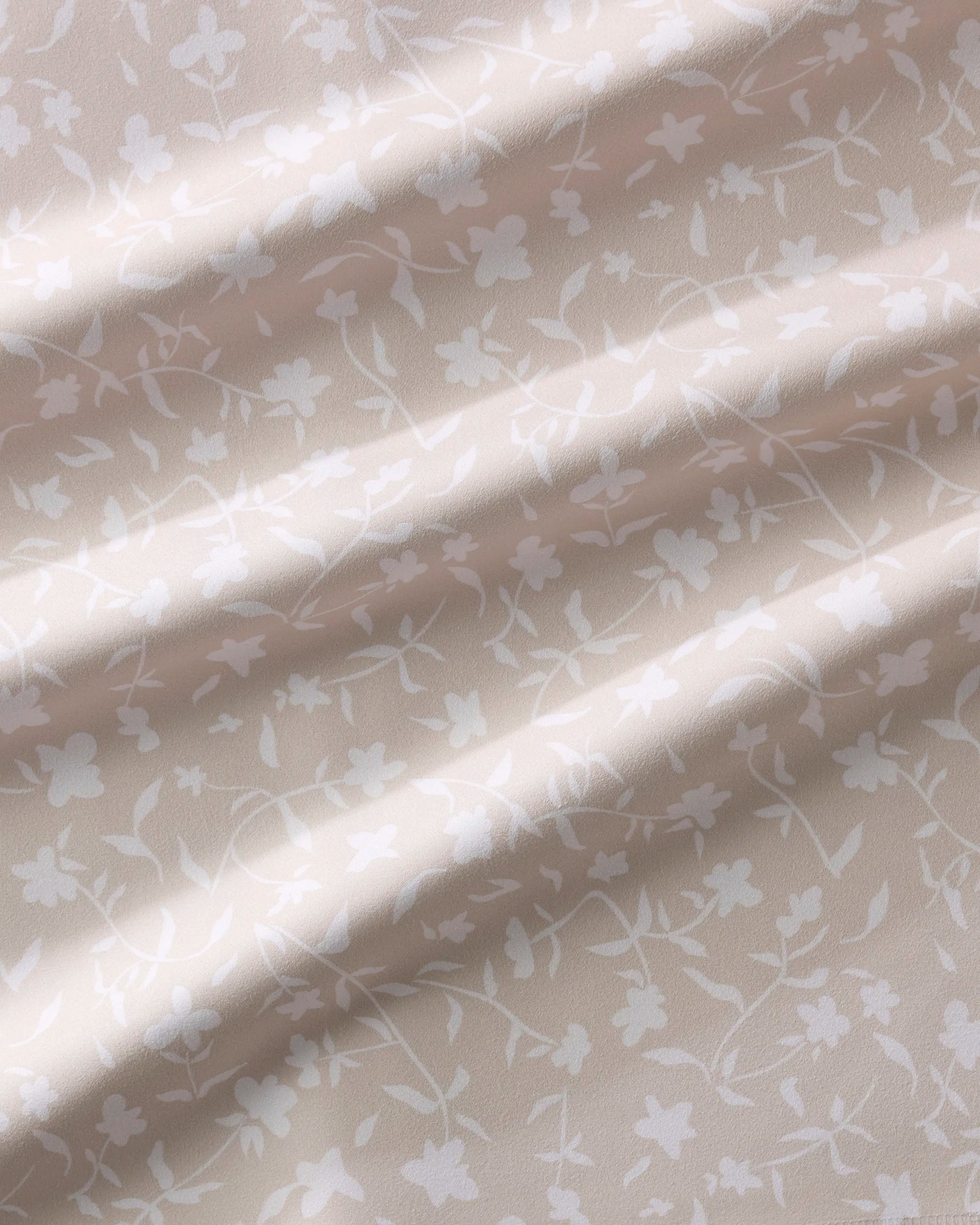 A close-up of Aubrey Fairchild's Tiny Floral fabric in light beige, featuring a subtle white floral pattern and soft folds—ideal for an elegant dinner napkin set.